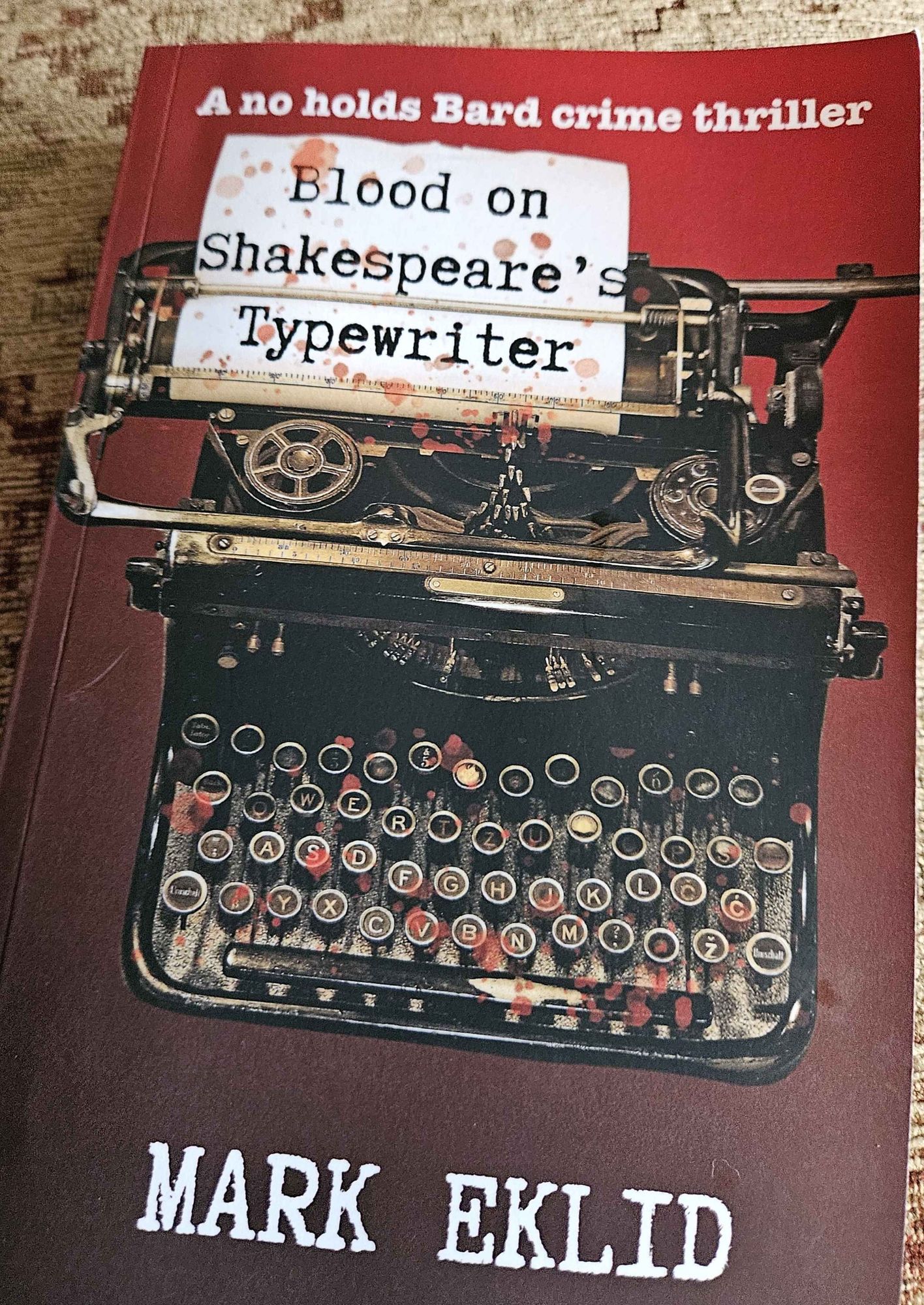 Book cover shows a typewriter spattered with red, Title is Blood on Shakespeare's Typewriter by Mark Eklid. Five stars book, I'm loving it!