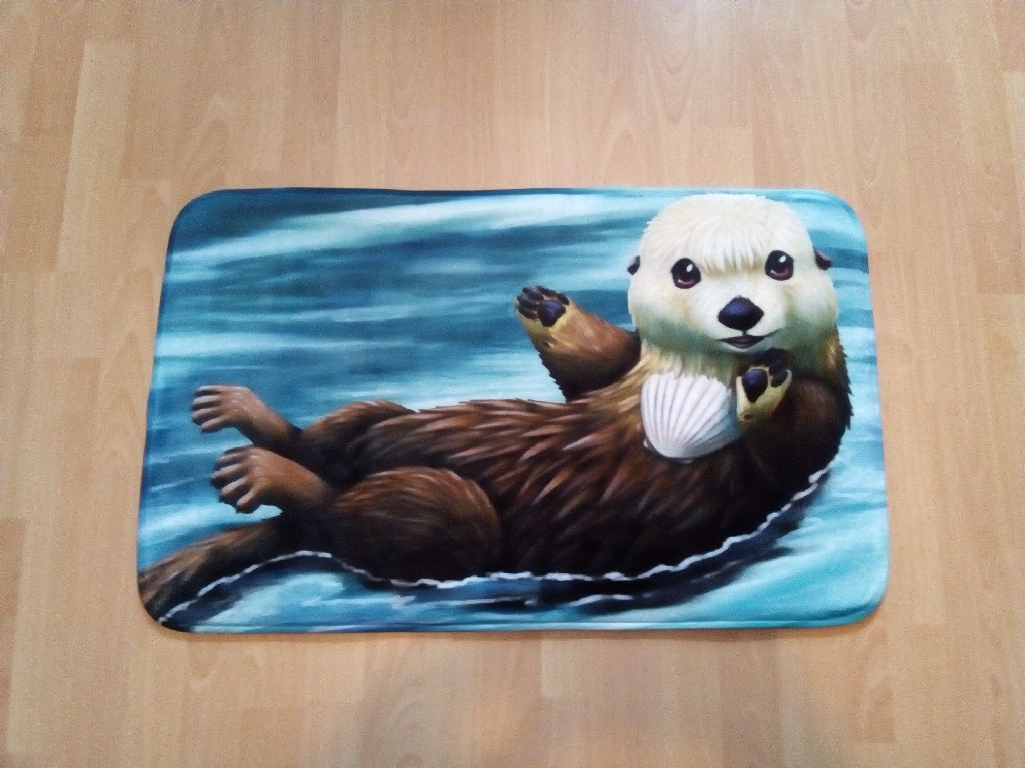 A photo of a bath mat with an illustration of a cute sea otter on it. I got this for my sister so I can personally guarantee the quality.