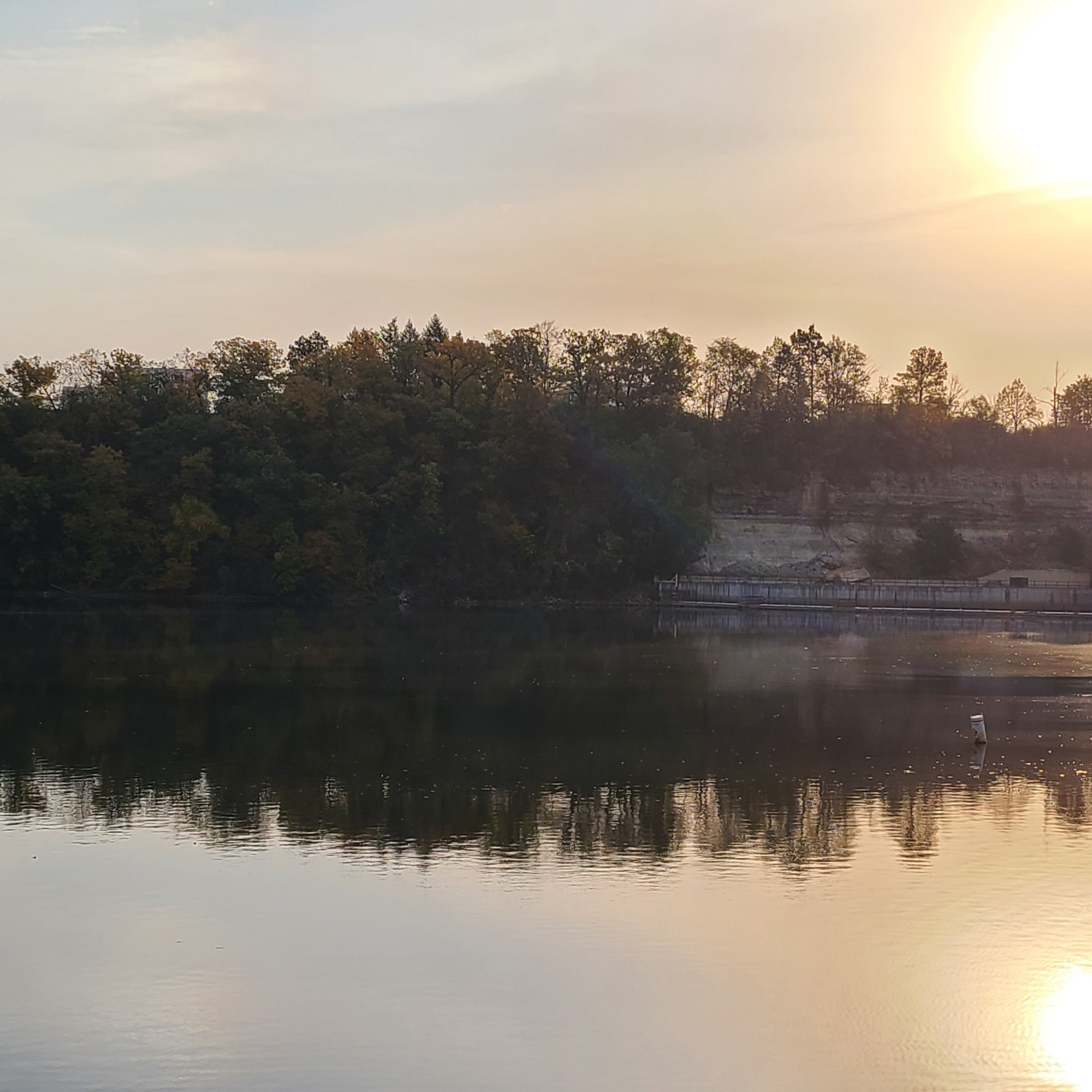 Sun reflecting off still Mississippi River, trees behind on St Paul side