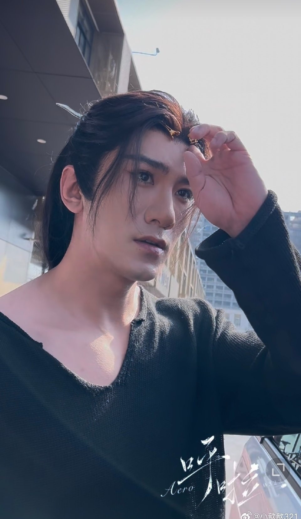 Xiao Shunyao in his wig and hair clips, in a black sweater with a nice neckline