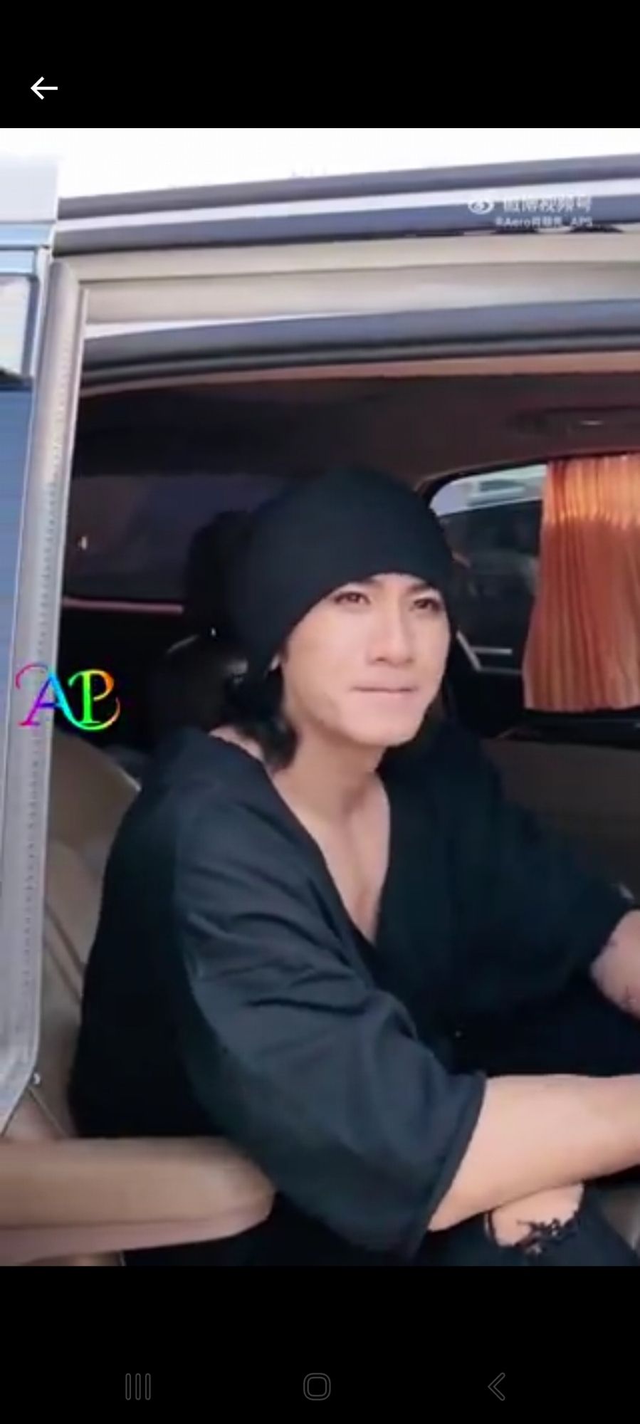 Xiao Shunyao in a black sweater with a very deep v-neckline and a black beanie