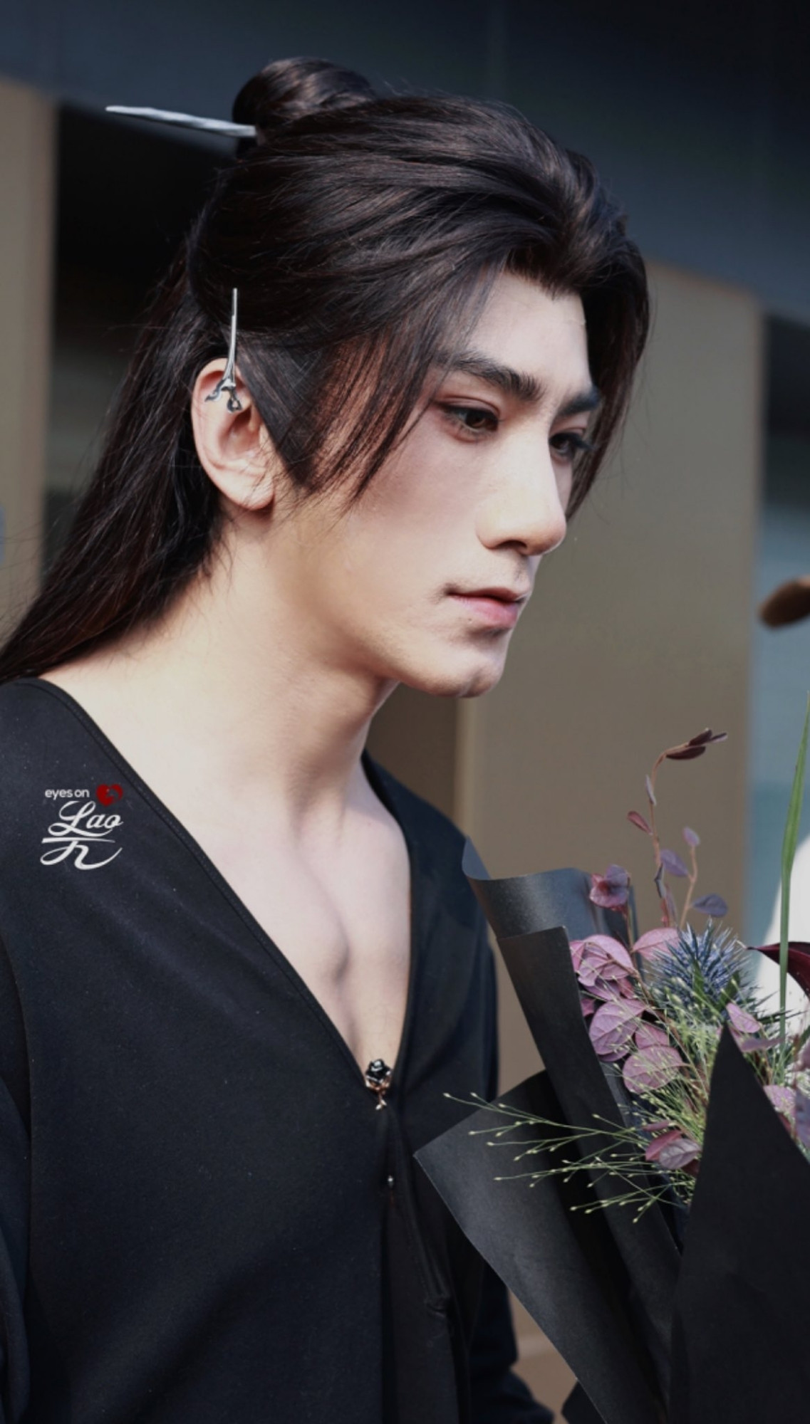 Xiao Shunyao in a long black wig and a black shirt with a deep neckline,  holding some flowers