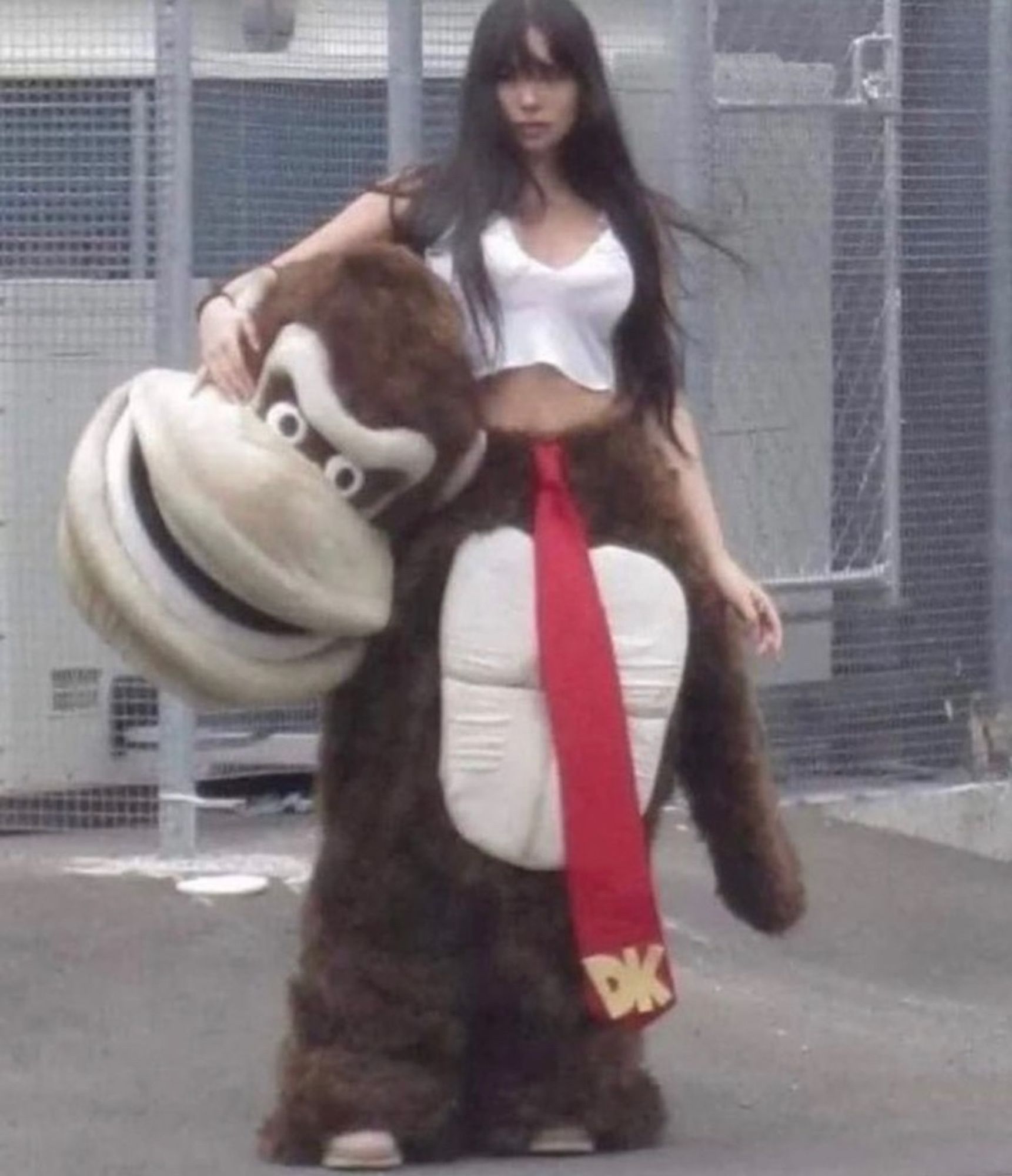 a woman inside of a Donkey Kong costume holding the head/mask under her arm