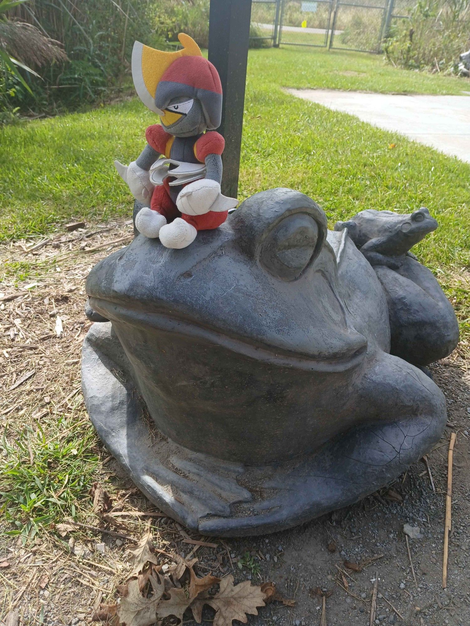 A Bisharp plush sitting on a happy looking frog statue