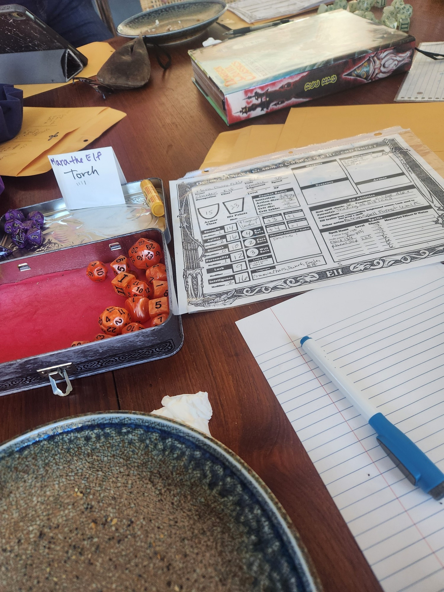 A table with a Dungeon Crawl Classic character sheet and a box of dice 