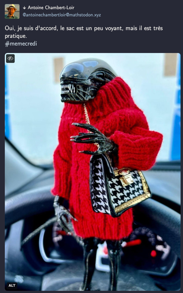 image : une figurine de xenomorphe (monstre de la saga Alien) habillée avec une robe en laine rouge et portant un sac à main en bandoulière

Texte de Antoine : Oui, je suis d'accord, le sac est un peu voyant, mais il est très pratique