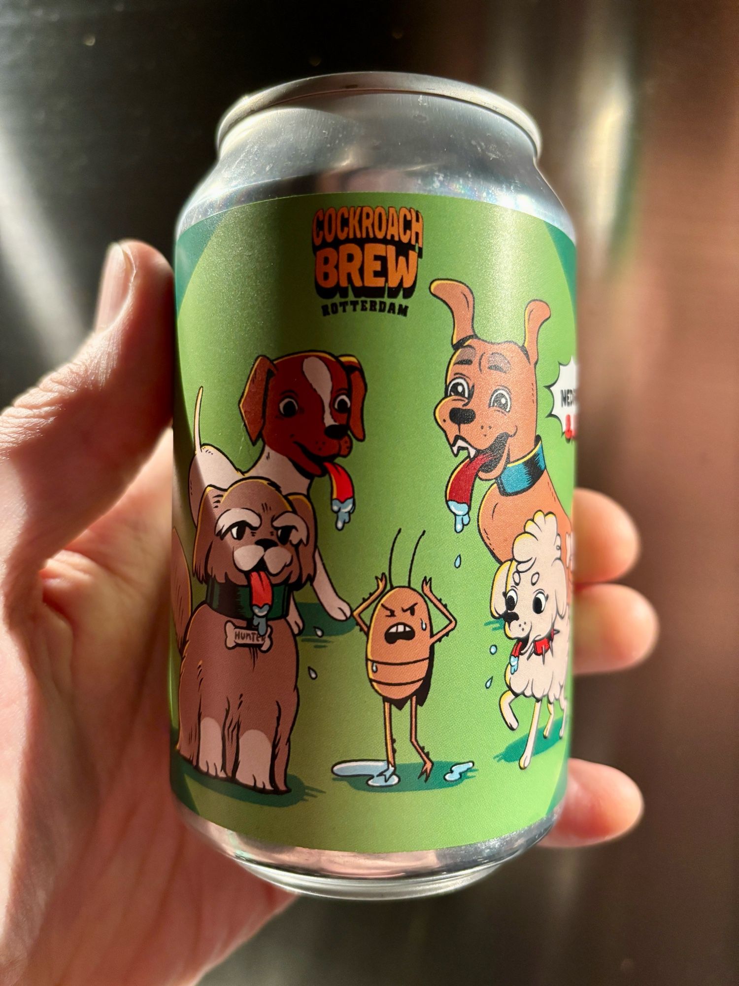 Een blikje Can I Lick It?, een double NEIPA van Cockroach Brew uit Rotterdam. Het label is groen met daarop een tekening van diverse honden met natte tongen uit hun bek, en een kakkerlak die niet blij kijkt.