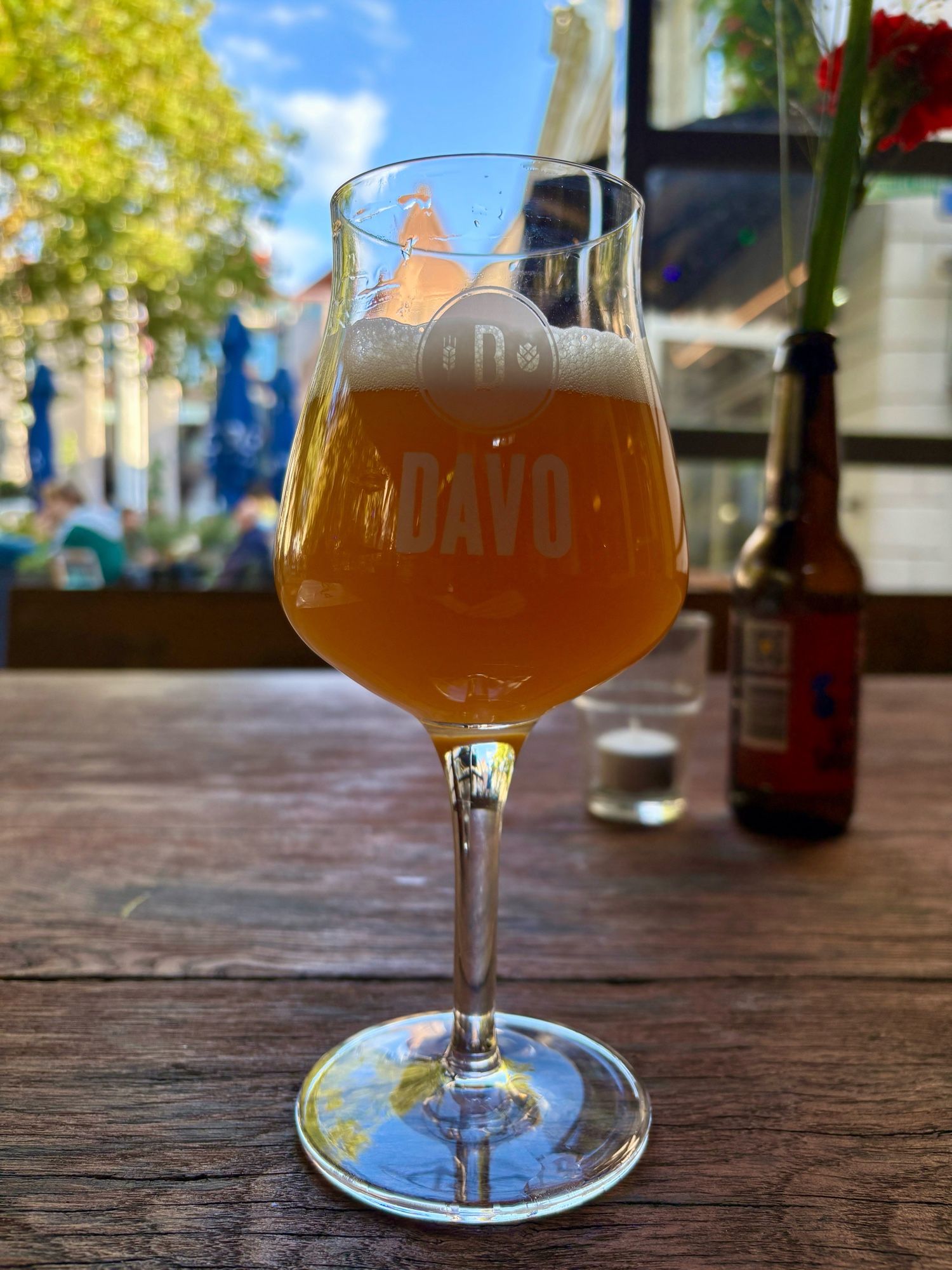 Een speciaalbier glas met in wit het DAVO logo met tarwe en hop erop, en erin Rolling Papers, een NEIPA van Bullhouse Brew Co.