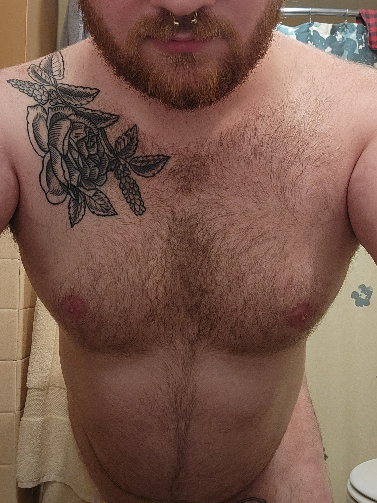 Standing with my arms on the wall behind the camera to show off my chest and tummy. Completely naked but covering my genitals