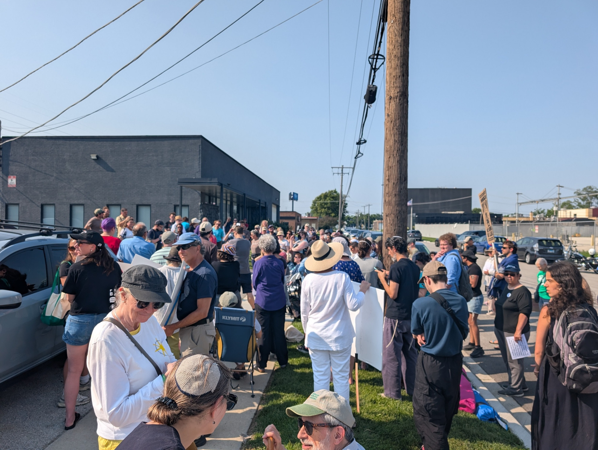 A crowd of people gathered outside a non-descript government building on the sidewalk.