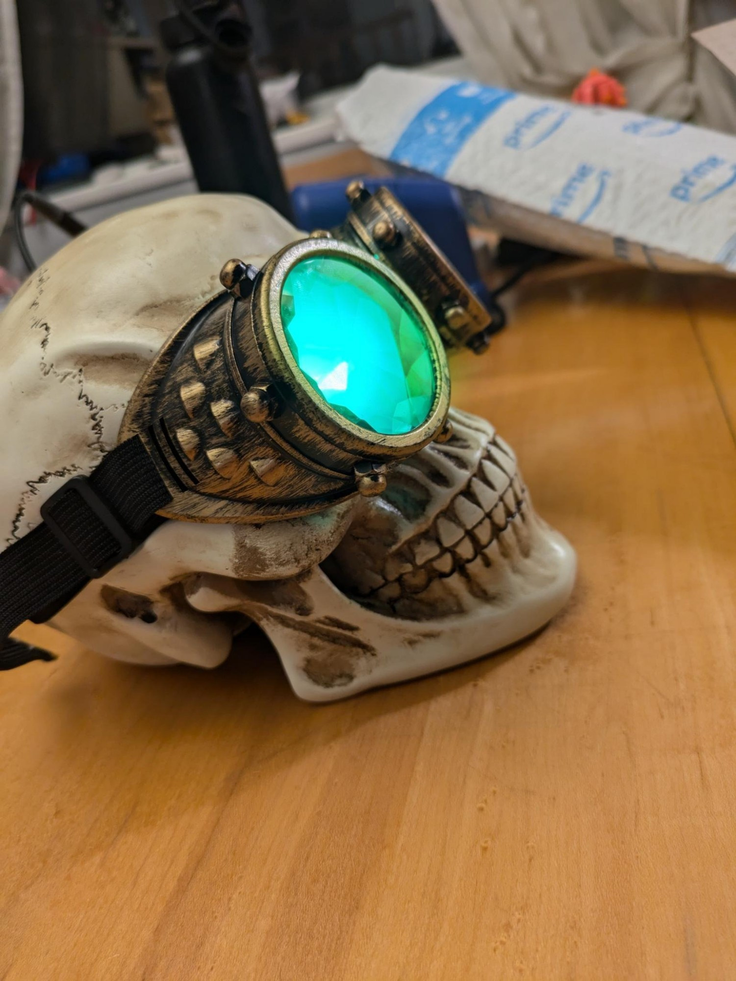 A plastic skull wearing kaleidoscope goggles with green LEDs dressed up to look like Manfred from Dragon age the veilguard