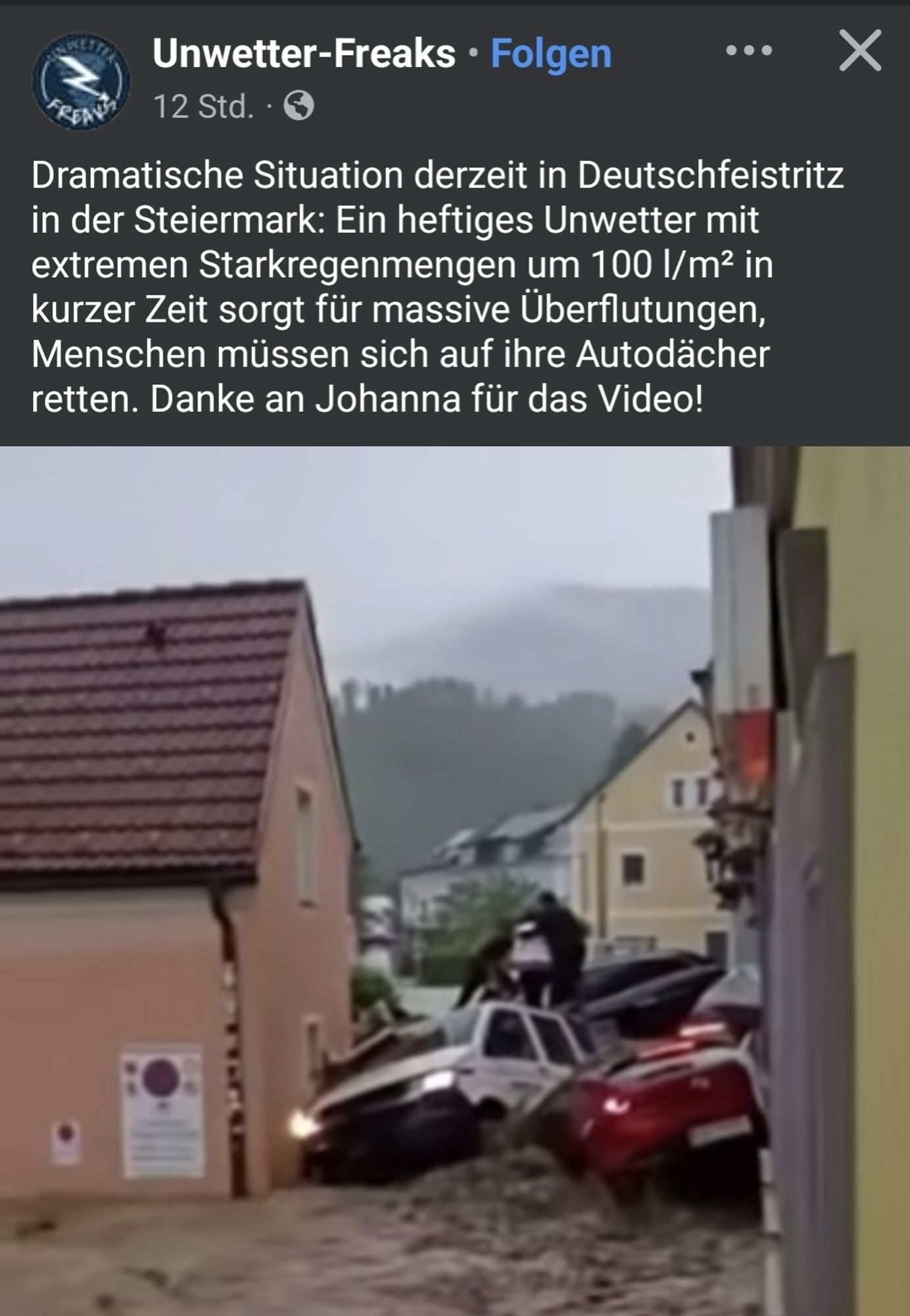 Screenshot aus video von Unwetter-freaks. "dramatische Situation in Deutschfeistritz. Heftiges Unwetter, Starkregenmengen um 100l pro Quadratmeter. Massive Überflutungen". Zu sehen sind mehrere PKW, die die Fluten zwischen zwei Häusern verkeilt und teilweise übereinander gestapelt haben.