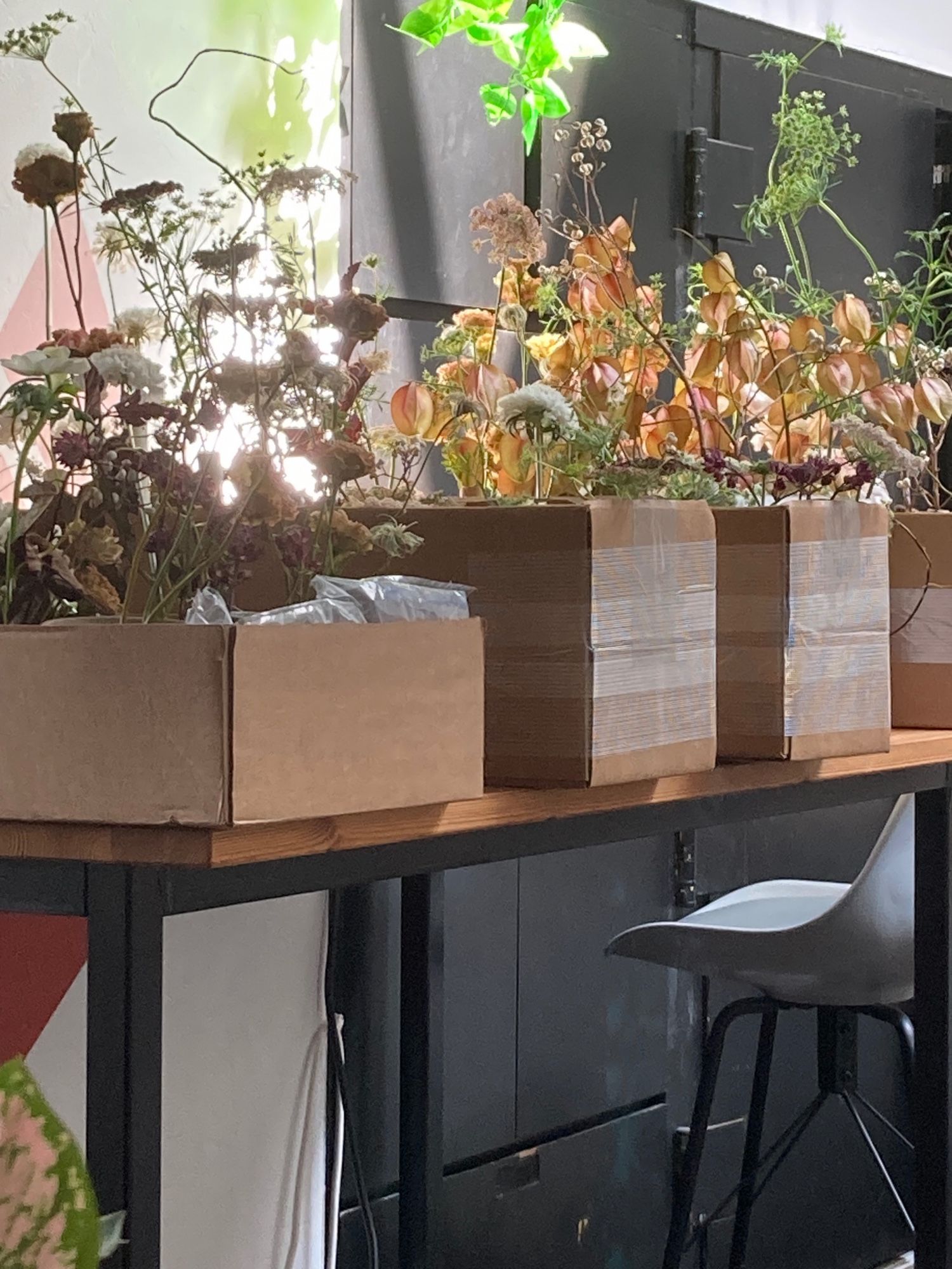 Co-working desk covered with boxes of autumnal flower arrangements