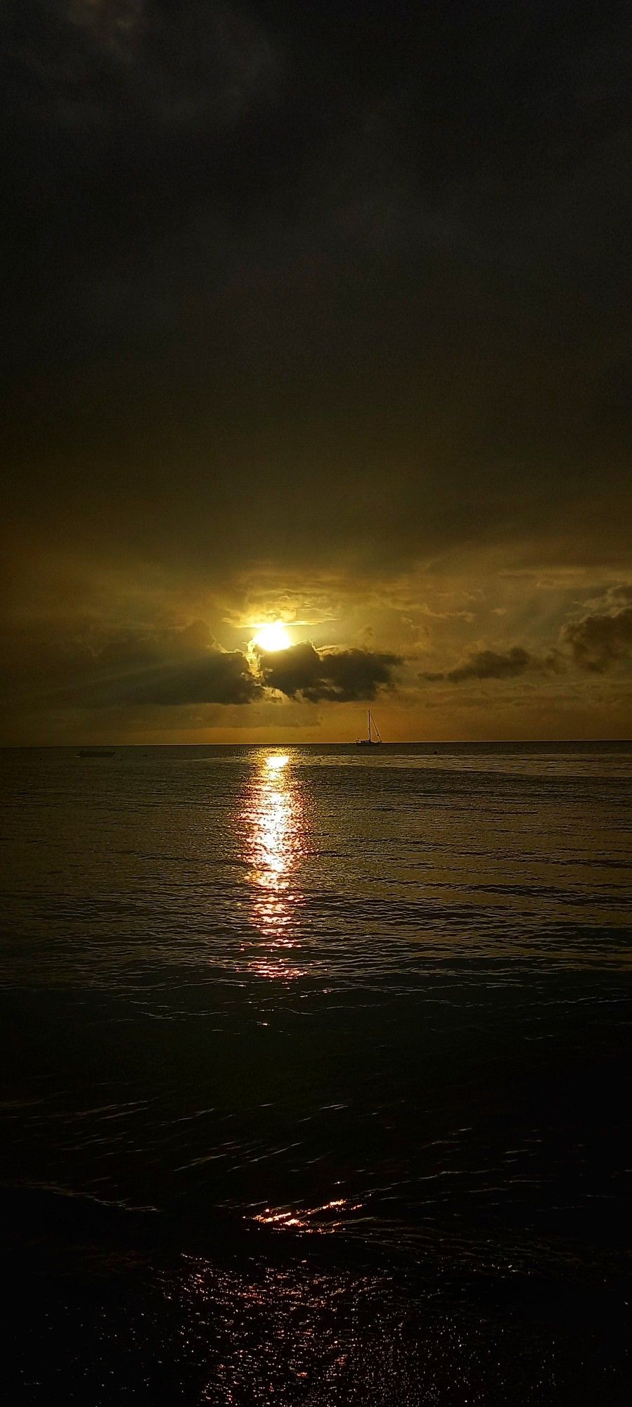 Sun getting ready to set in shades of yellow over a calm sea