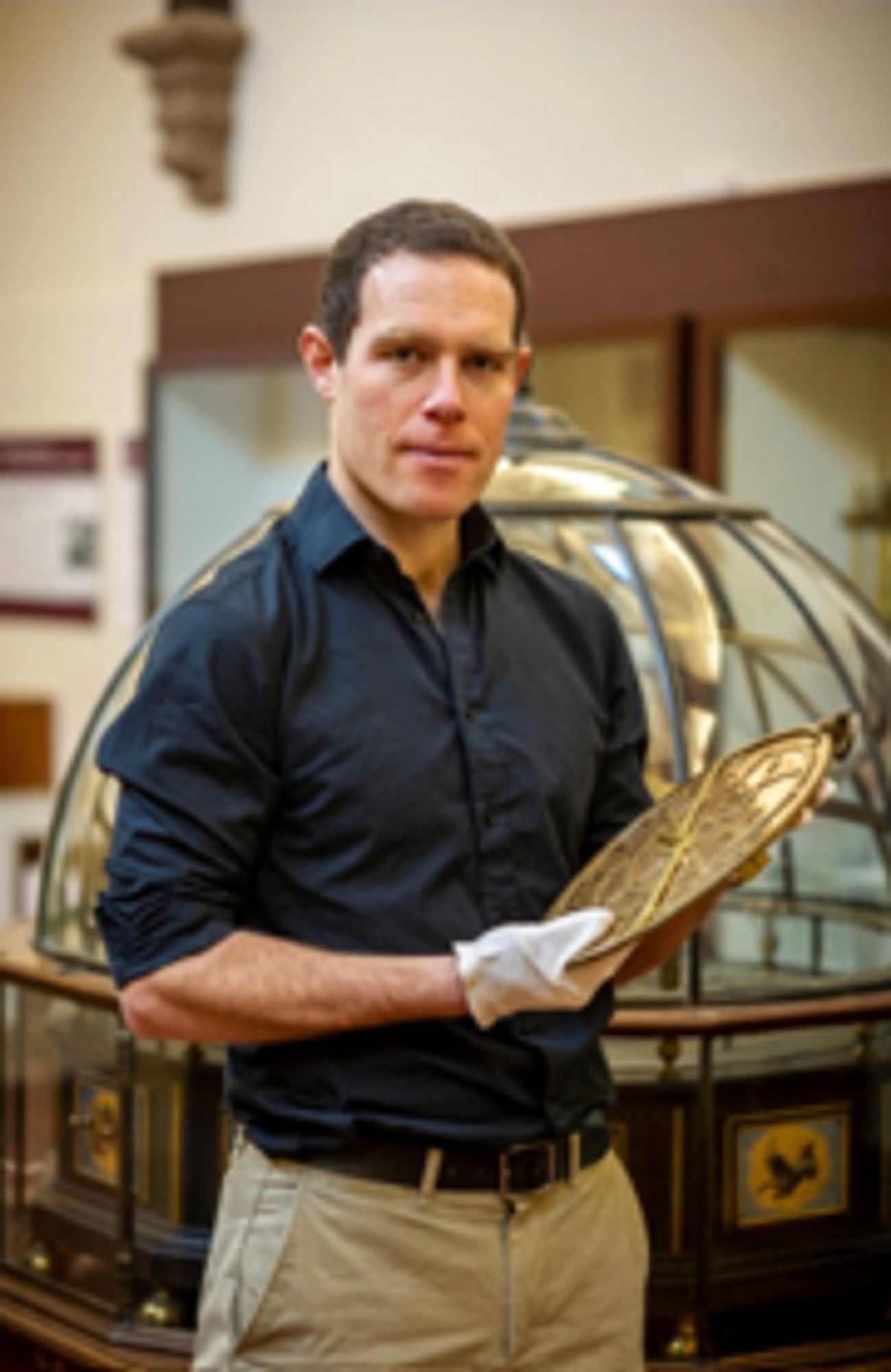 Seb Falk holding an antique astrolabe.