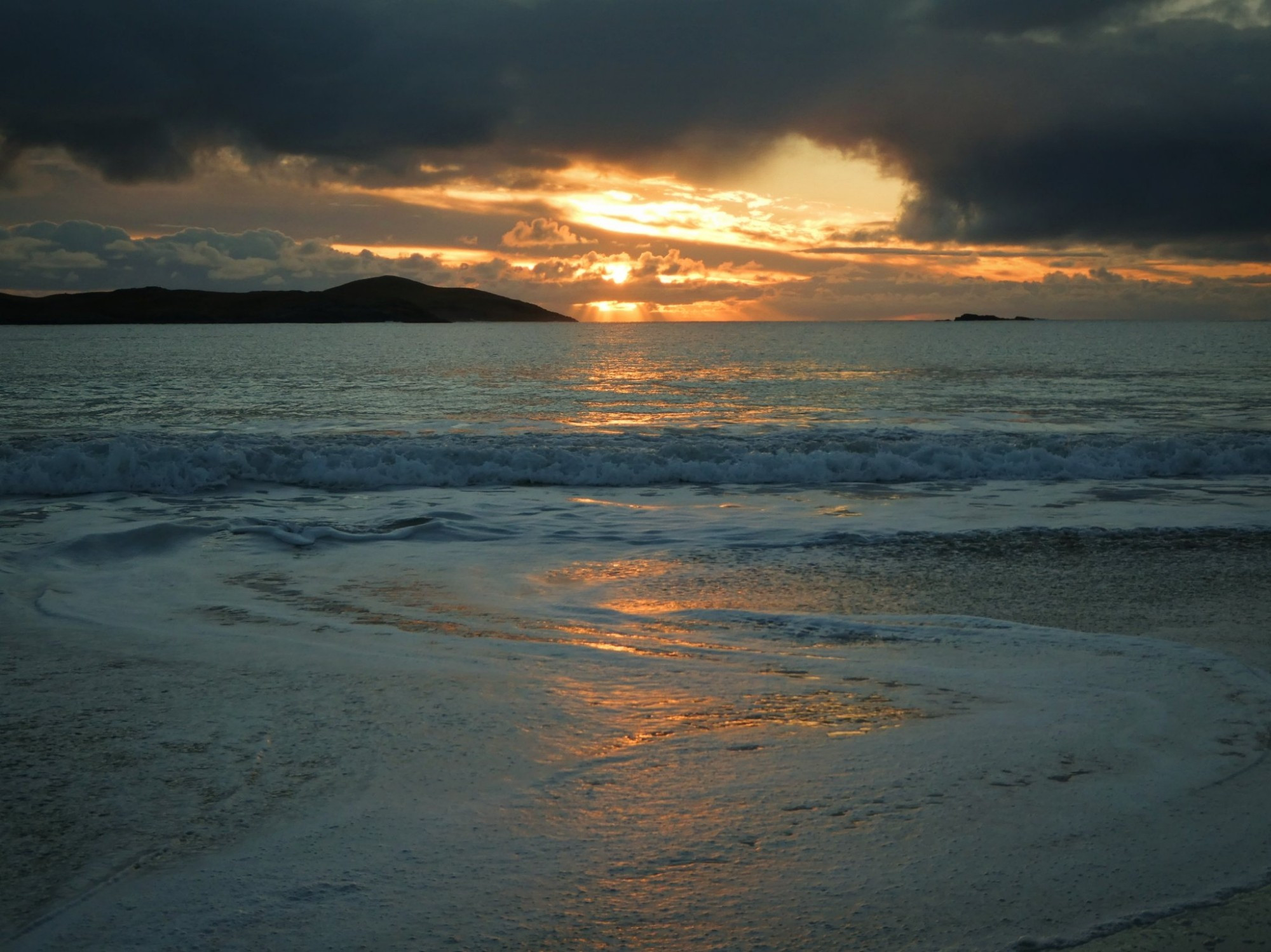 Image shows a sunset over the sea. Orange light forms a path on waters surface