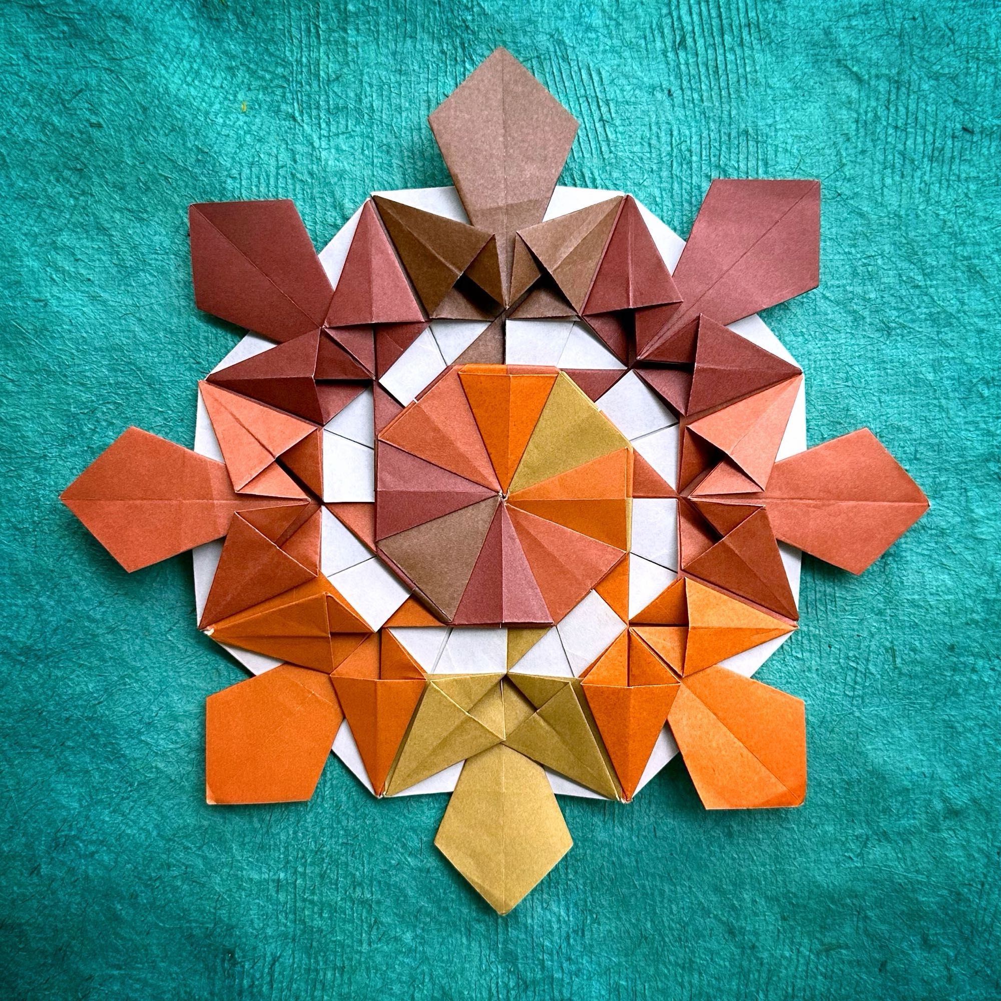 Photo of a modular origami mandala in shades of brown and white, on a turquoise background