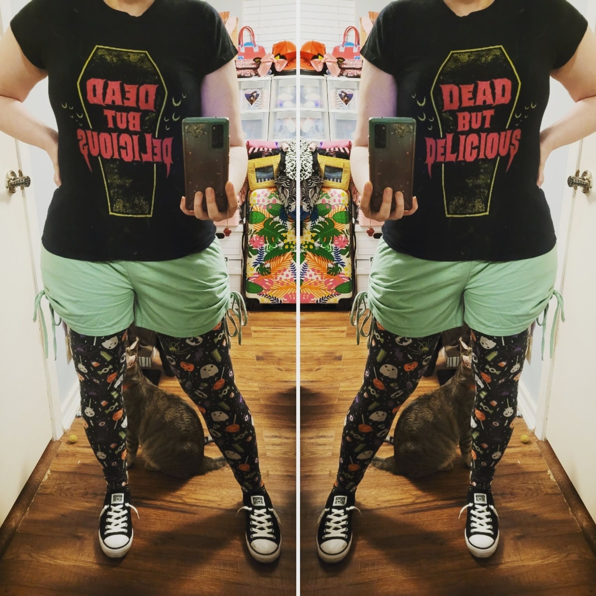 Outfit of a 53 year old lady wearing a black t-shirt that reads "Dead But Delicious" with mint green shorts over Halloween candy & ghost printed leggings from Cat & Jack, with black Converse low rise sneakers. A light brown stripey tabby cat is visible sitting just behind her.