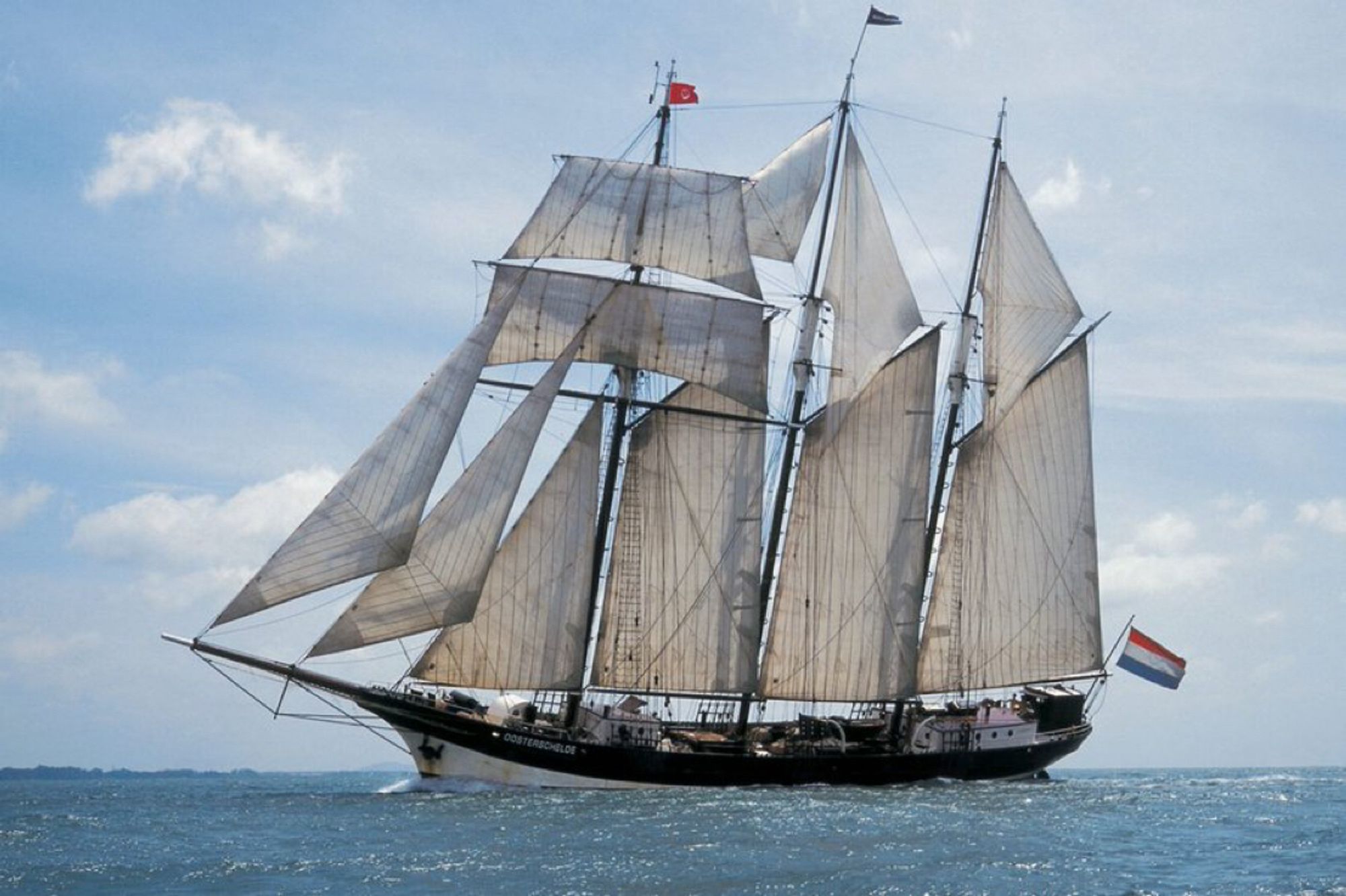 A historic tall ship with its sails up on the open seas