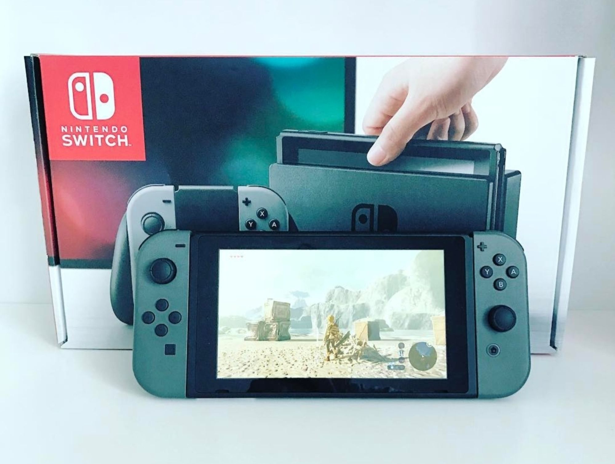 Bild der Nintendo Switch aus 2017 mit Breath of the Wild im Handheld Modus und der Originalverpackung dahinter