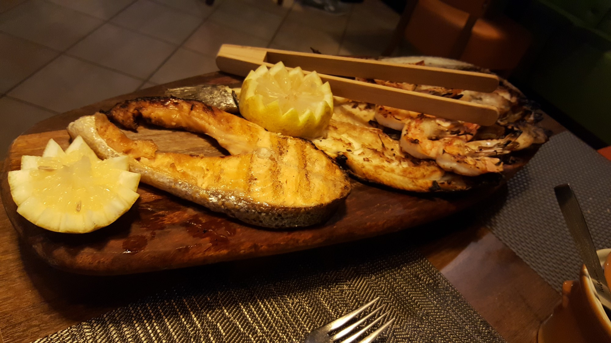 a platter of prawns, grilled salmon, sea bream, and sea bass with two huge cuts of lemon