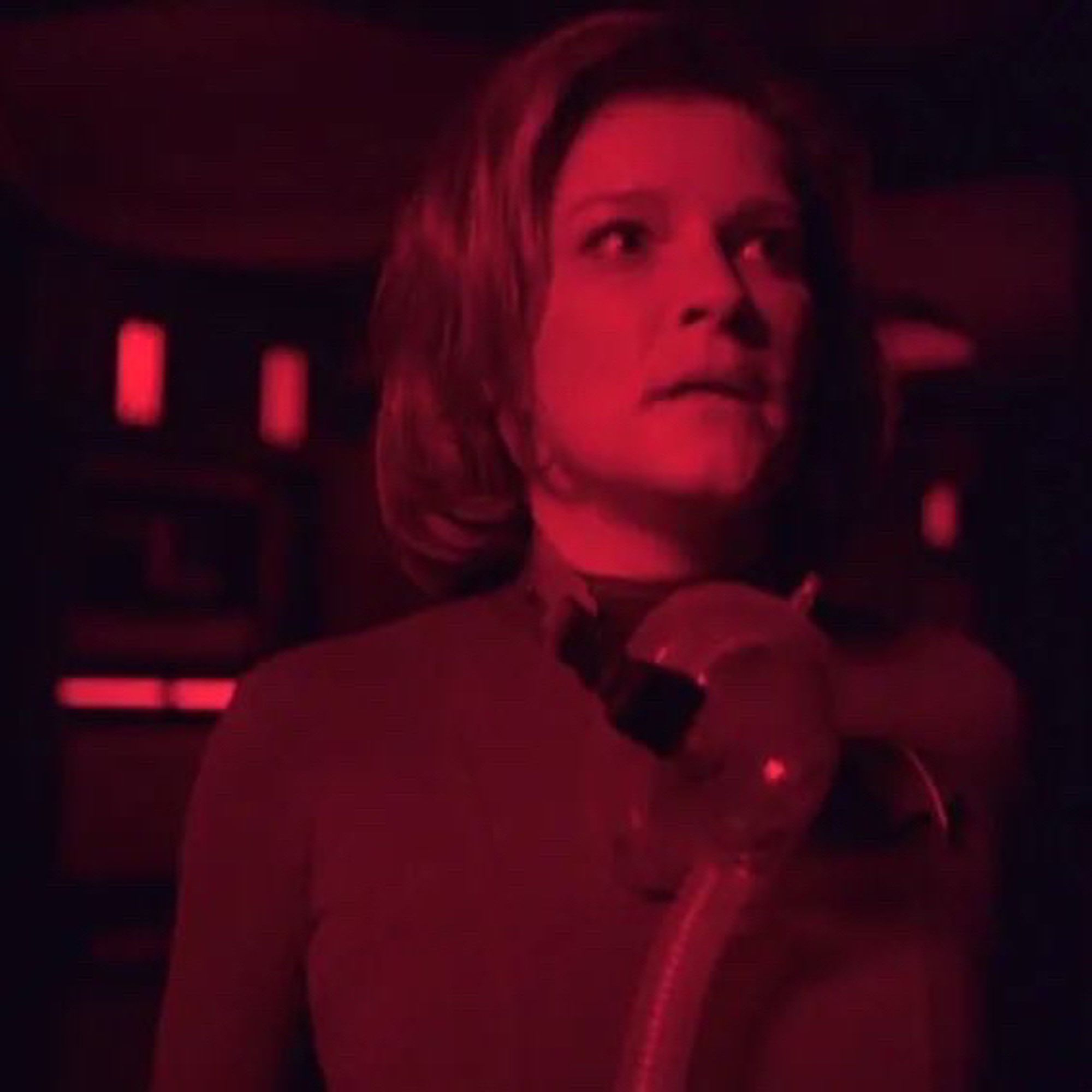 captain janeway stands in a corridor illuminated in emergency red and oxygen mask around her neck in the voyager episode “the haunting of deck 12”