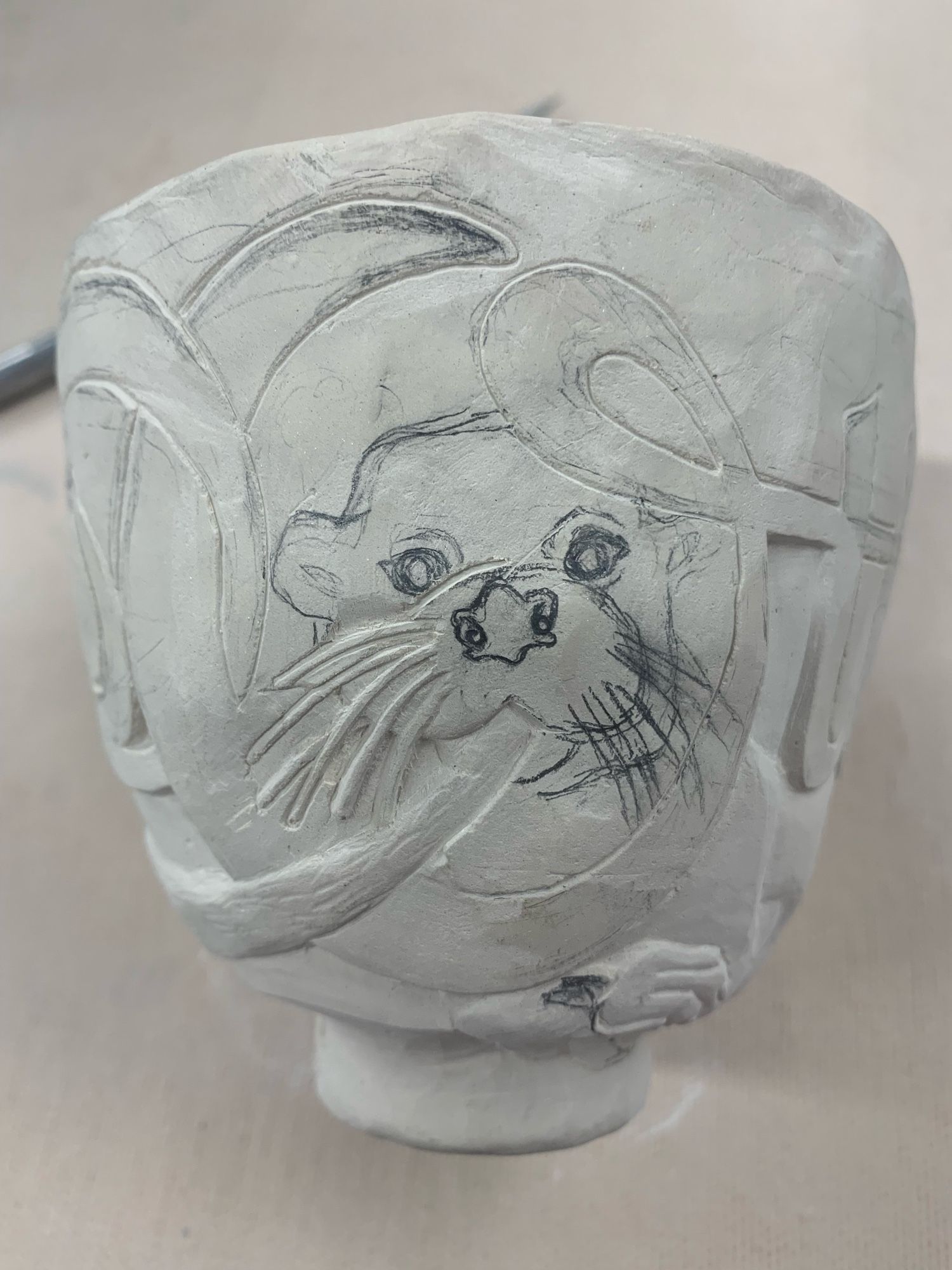 Greenware yunomi with the face of a river otter being carved