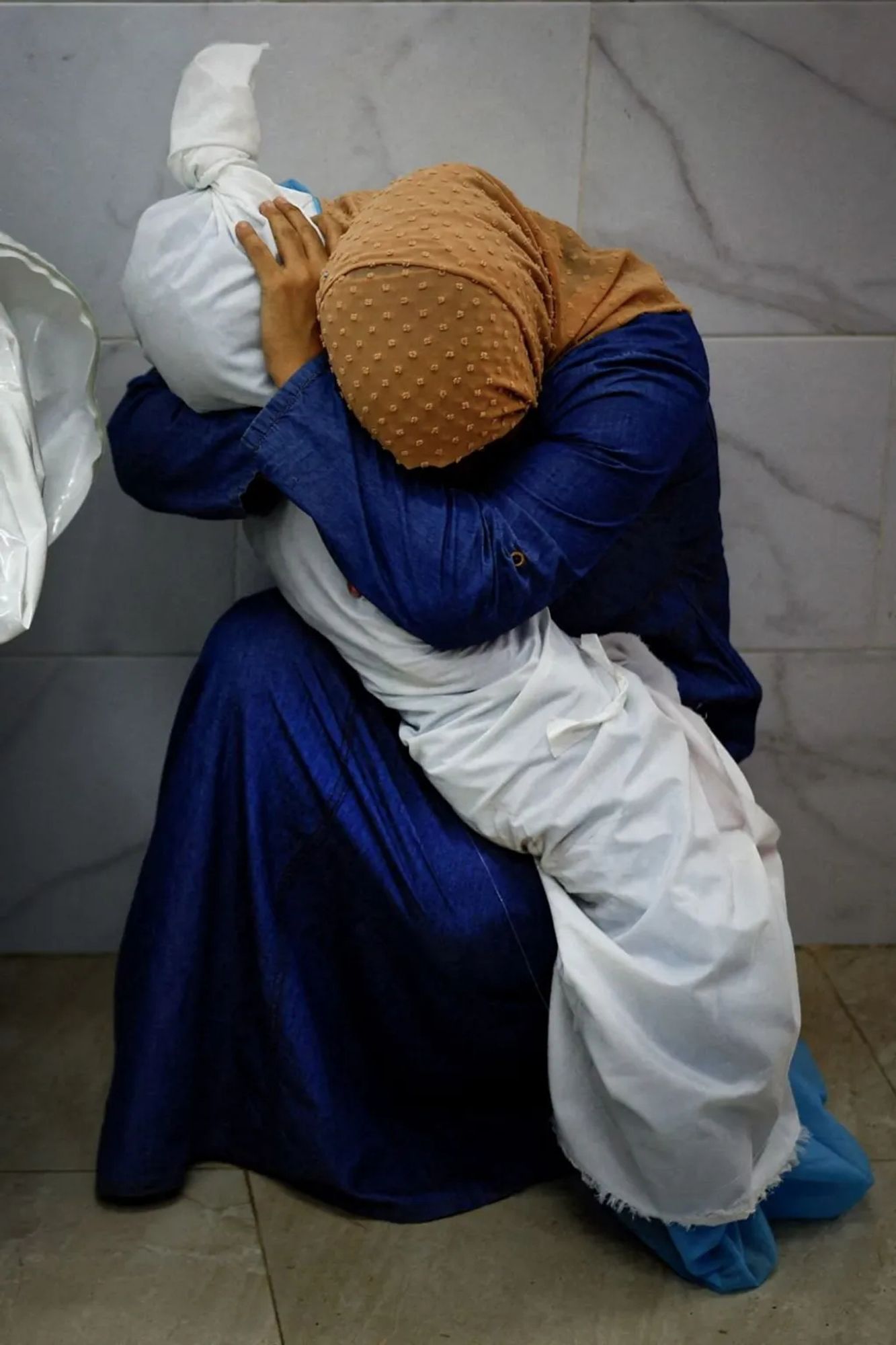 Mother in Gaza crying her tears dry with the dead body of her child wrapped in cloth in her arms