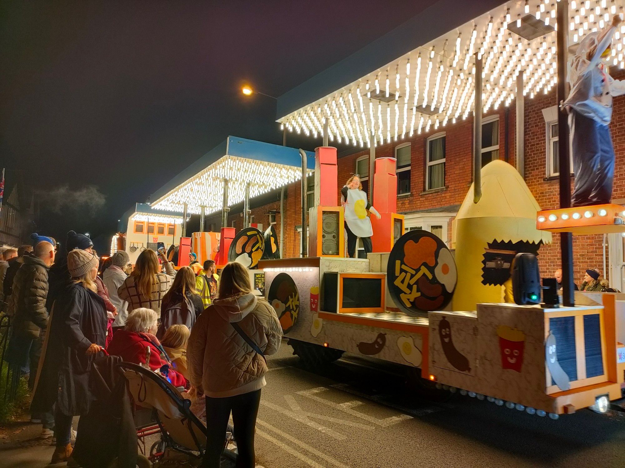 An illuminated carnival float with a food related theme.