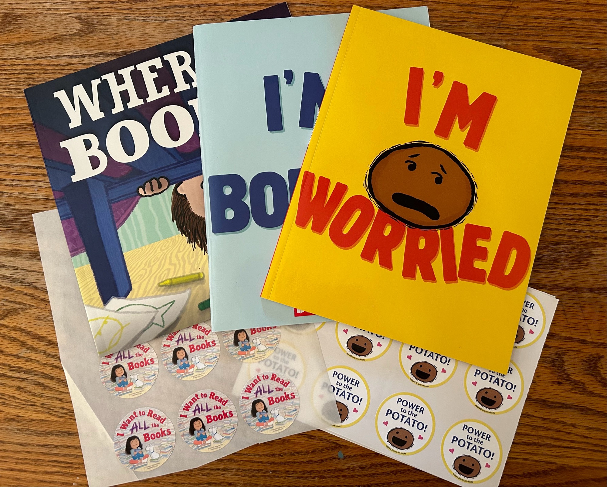 A copy of 3 of Debbie Ridpath Ohi’s paperbacks: WHERE ARE MY BOOKS, and two of her collaborations with Michael Black: I’M WORRIED & I’M BORED. Plus stickers of the potato character and stickers promoting her upcoming book: I WANT TO READ ALL THE BOOKS.