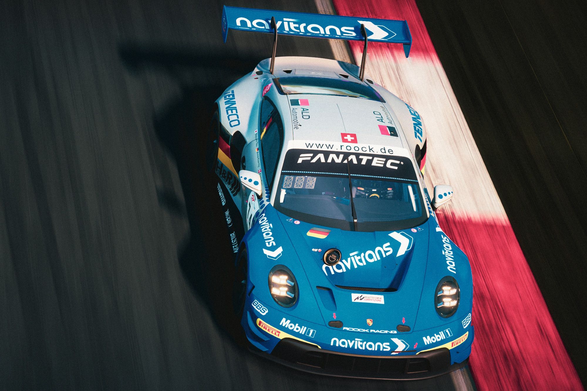 a metallic grey and blue Porsche 911 992 GT3 R sponsored by navitrans, edging on the outside kerb of a race track in a braking zone towards a corner