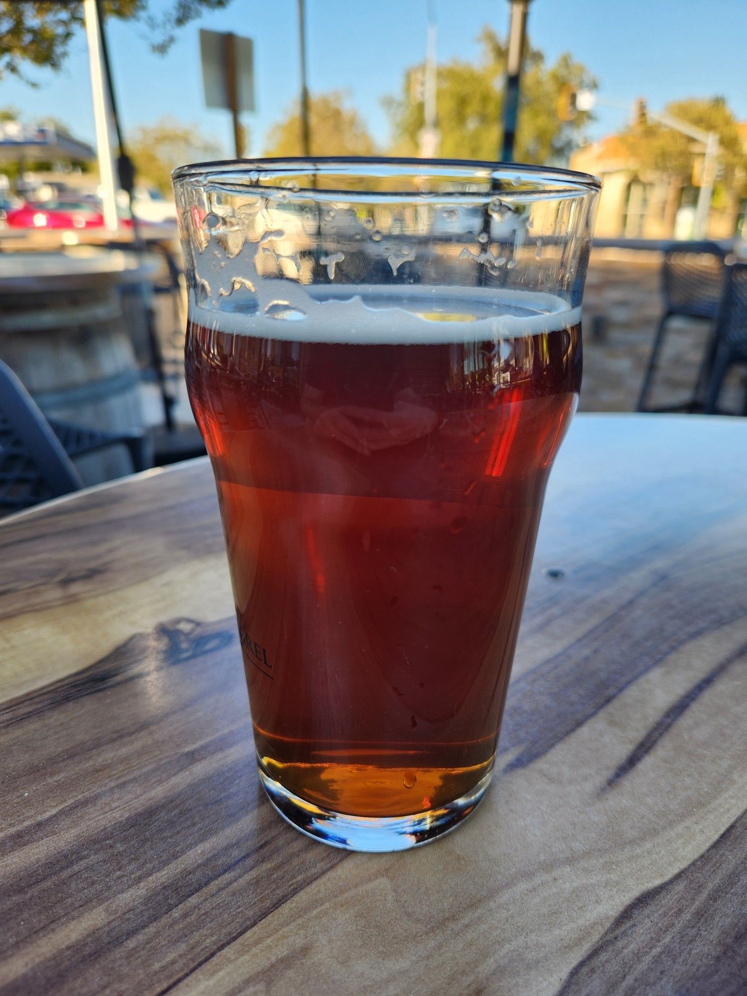 A pint of altbier sitting on a table outside.