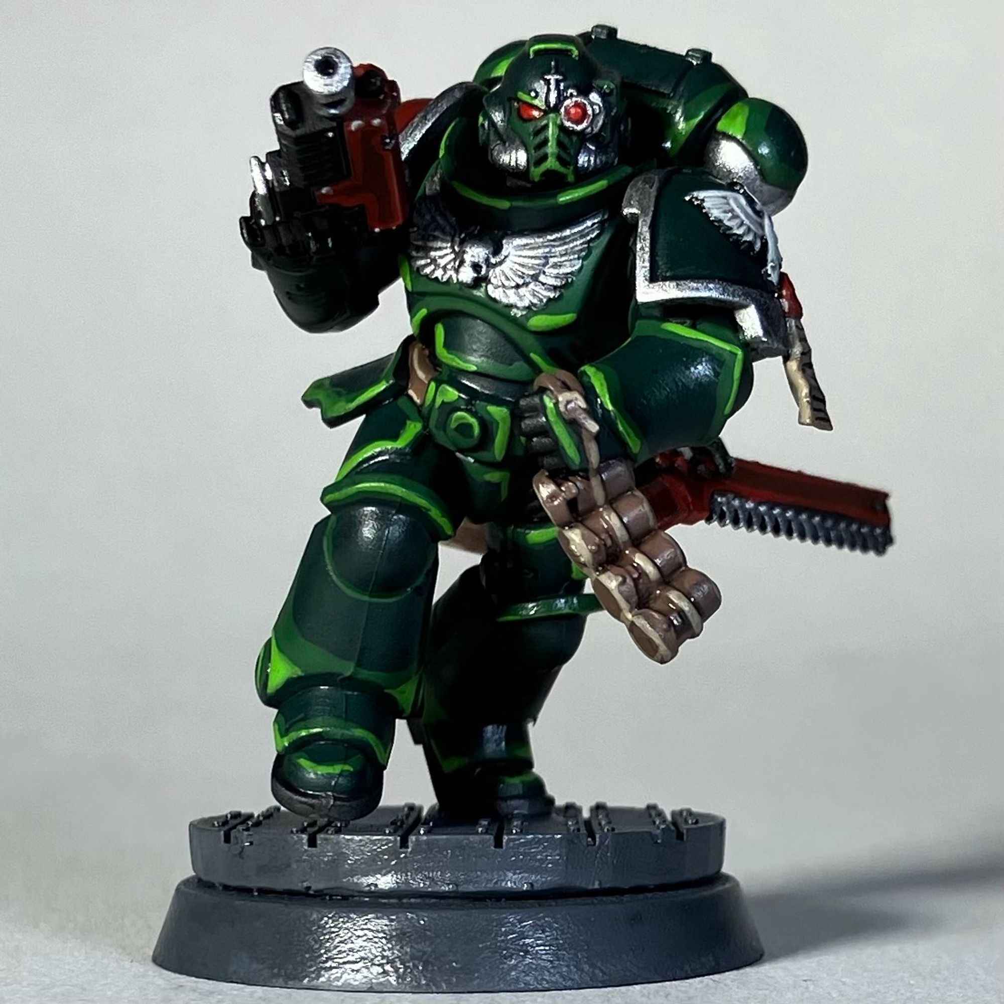 A Warhammer 40k Space Marine, Dark Angels Chapter, in green armor with a red weapon and red chainsword holdtered for the game Killteam