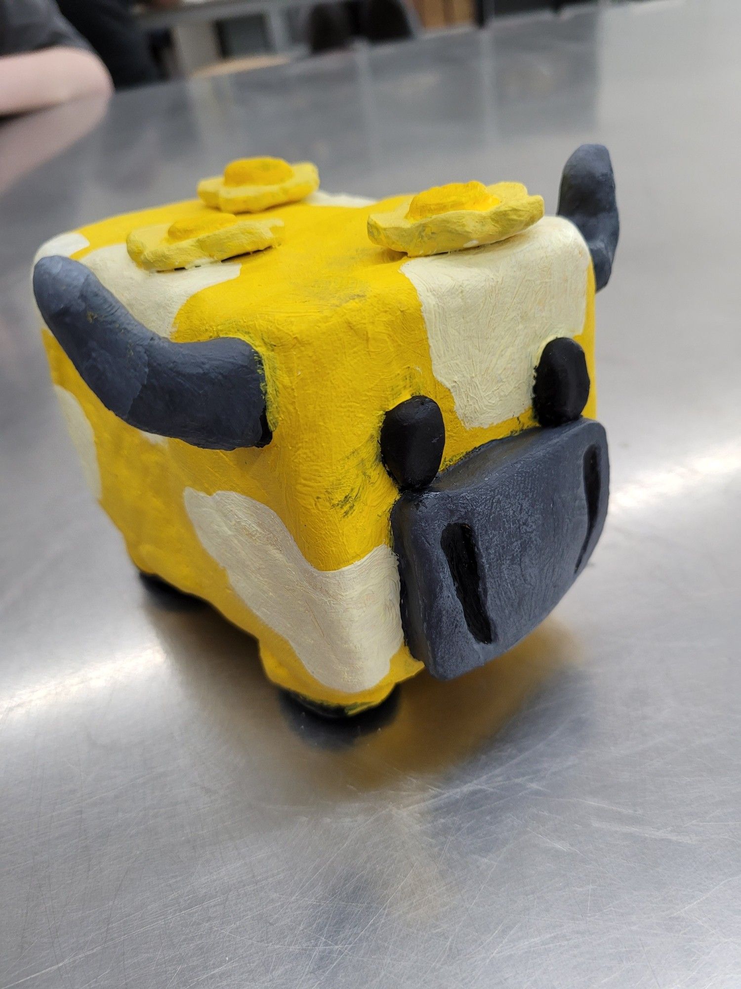 Fully painted ceramic moobloom sculpture. It's a yellow and white cow with buttercups on its back, from minecraft