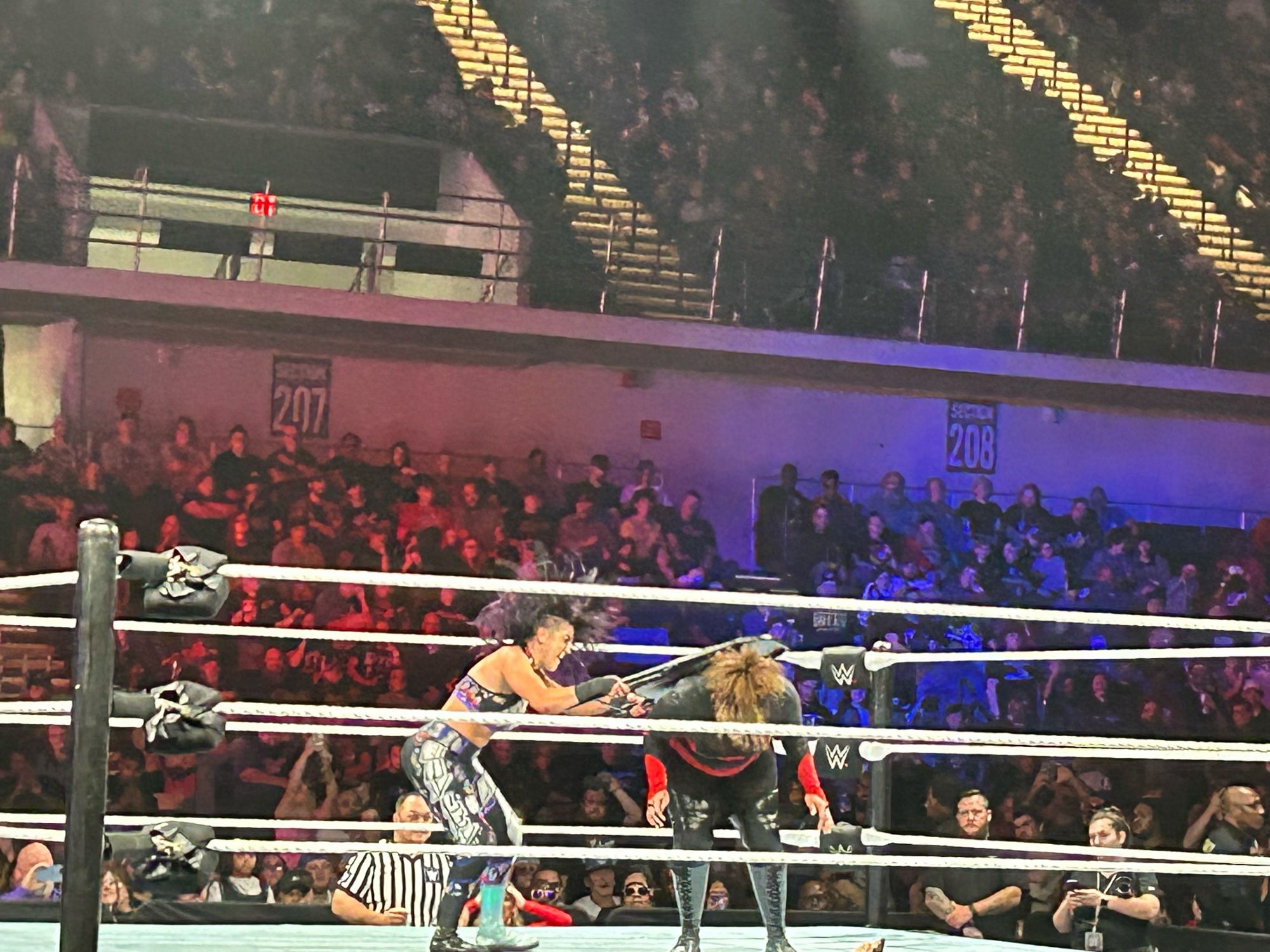 A candid photo of wrestler Bayley hitting Nia Jax across the back with a folding chair