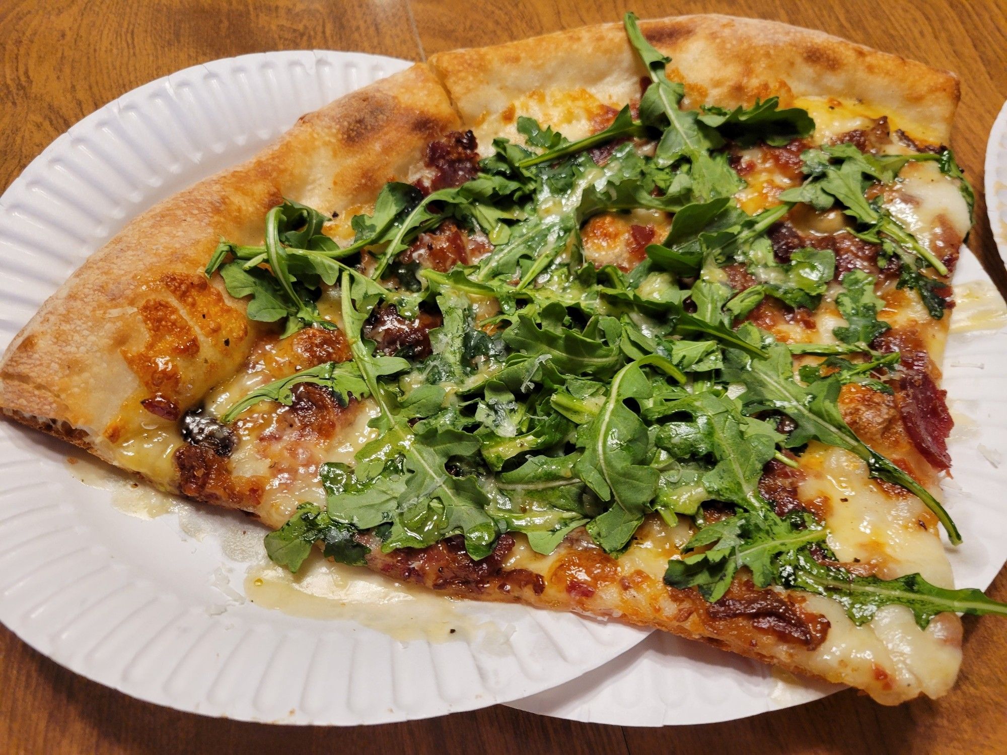 2 slices of pizza: white sauce, bacon, arugula, honey vinegarette, and shredded cheddar toppings.