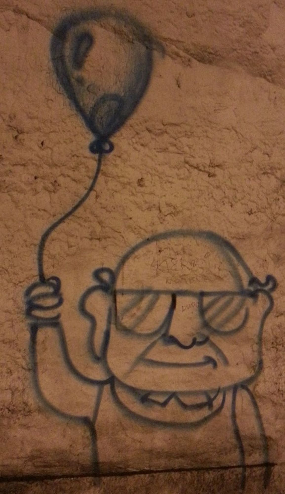 Crude spray-painted graffiti on a dingy old brown wall of Ed Asner's character from the movie Up holding a helium-filled balloon