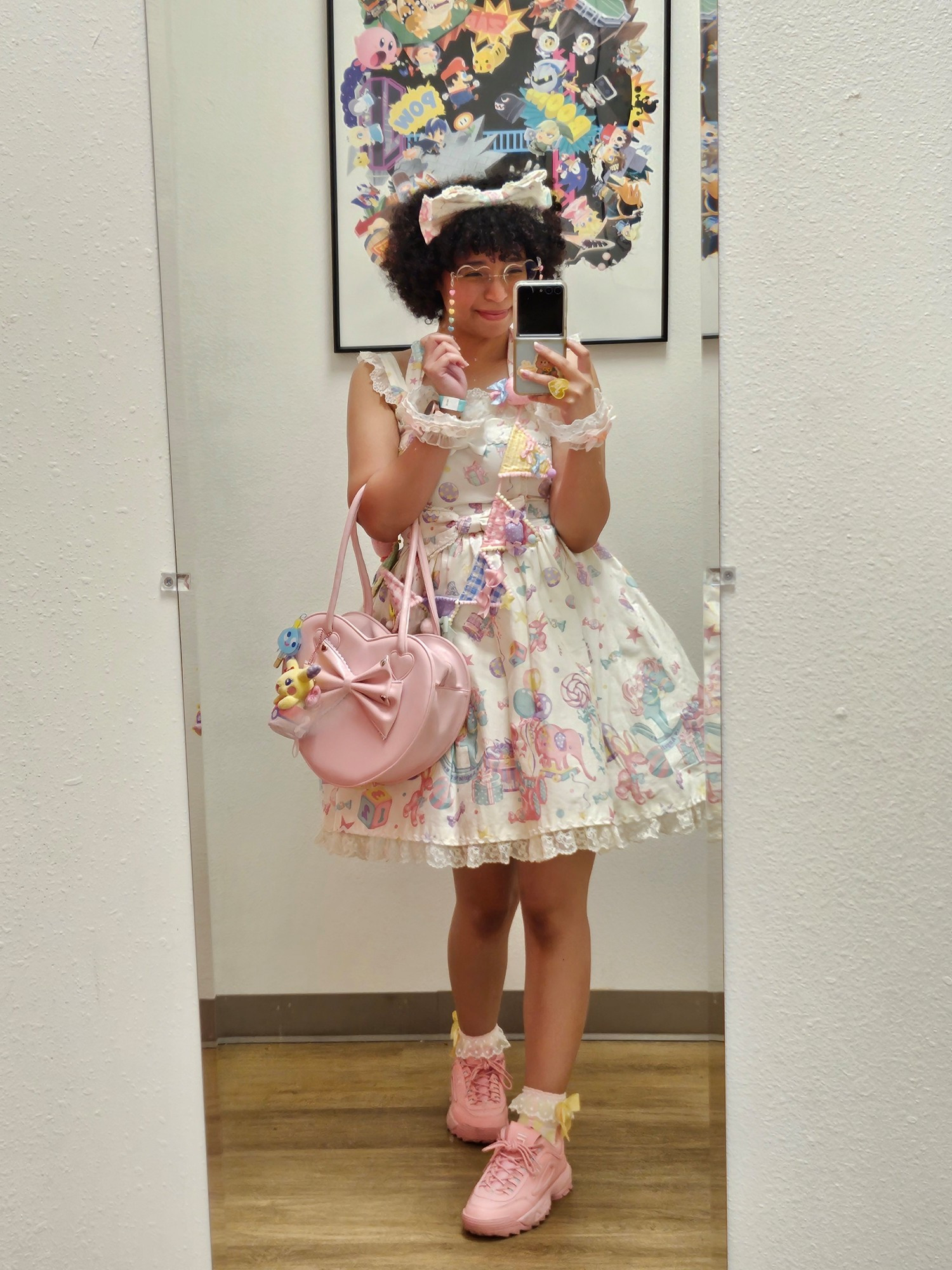 Taking a full body selfie in lolita fashion. The jsk is white with pastel colored rocking horses, elephants, balloons, bears and bunnies. She is using a multi pastel colored banner as a brooch across the dress, has a pink heart-shaped bag and pink Fila shoes. She has a white headbow, a multi pastel colored glasses chain that is in the shape of hearts, wristcuffs that are blue and pink and yellow and pink crew socks. 