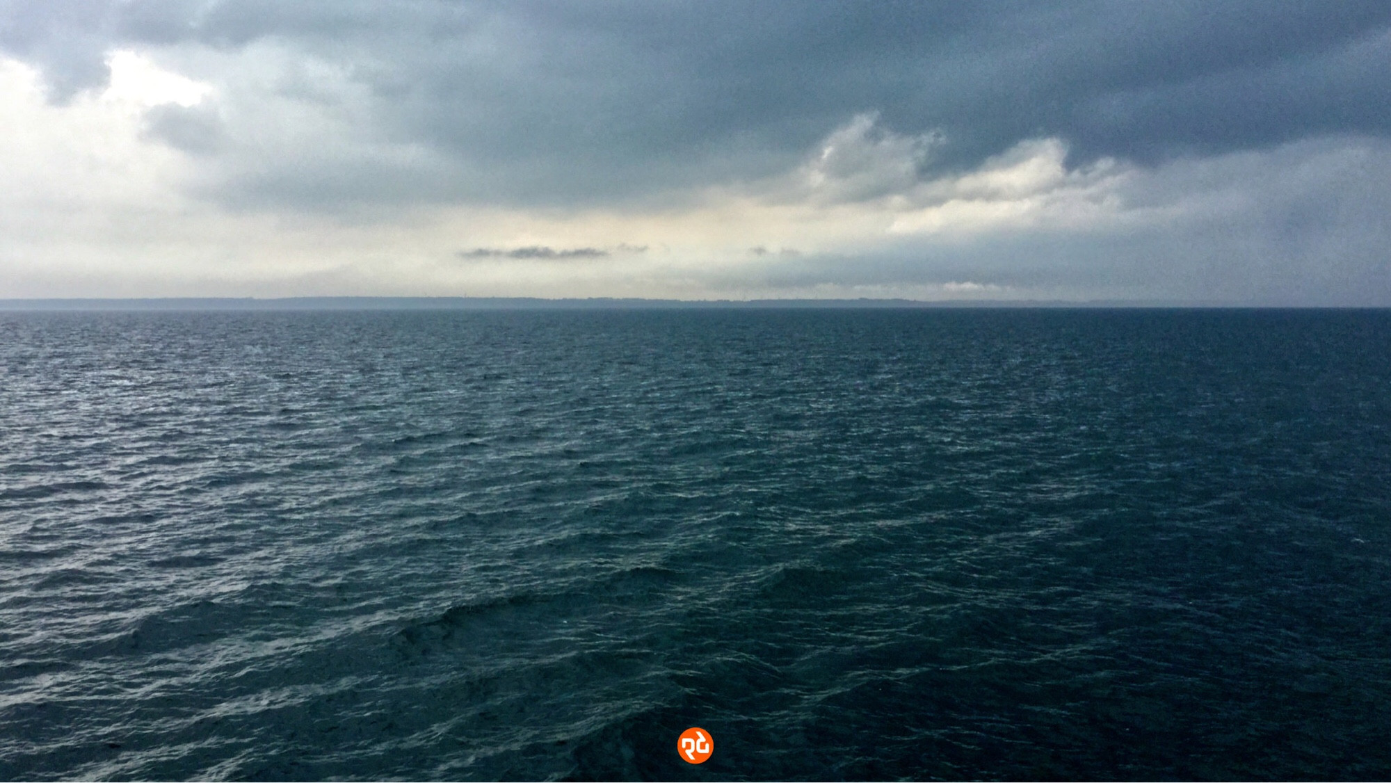 Farbfoto, Querformat: Blick aufs Meer bei Warnemünde. Blaugraue Wolken über stark gekräuseltem dunklen Wasser.