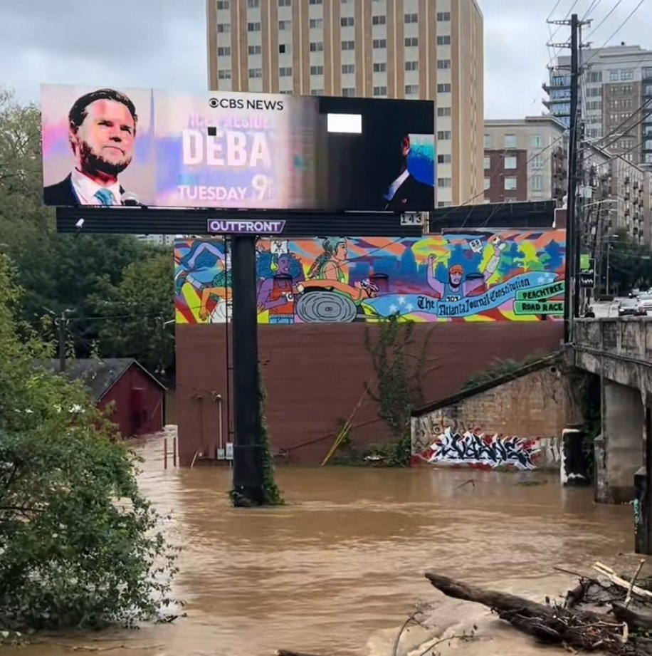 A digital billboard in Asheville, North Carolina advertising a presidential debate while glitching out in rising floodwaters