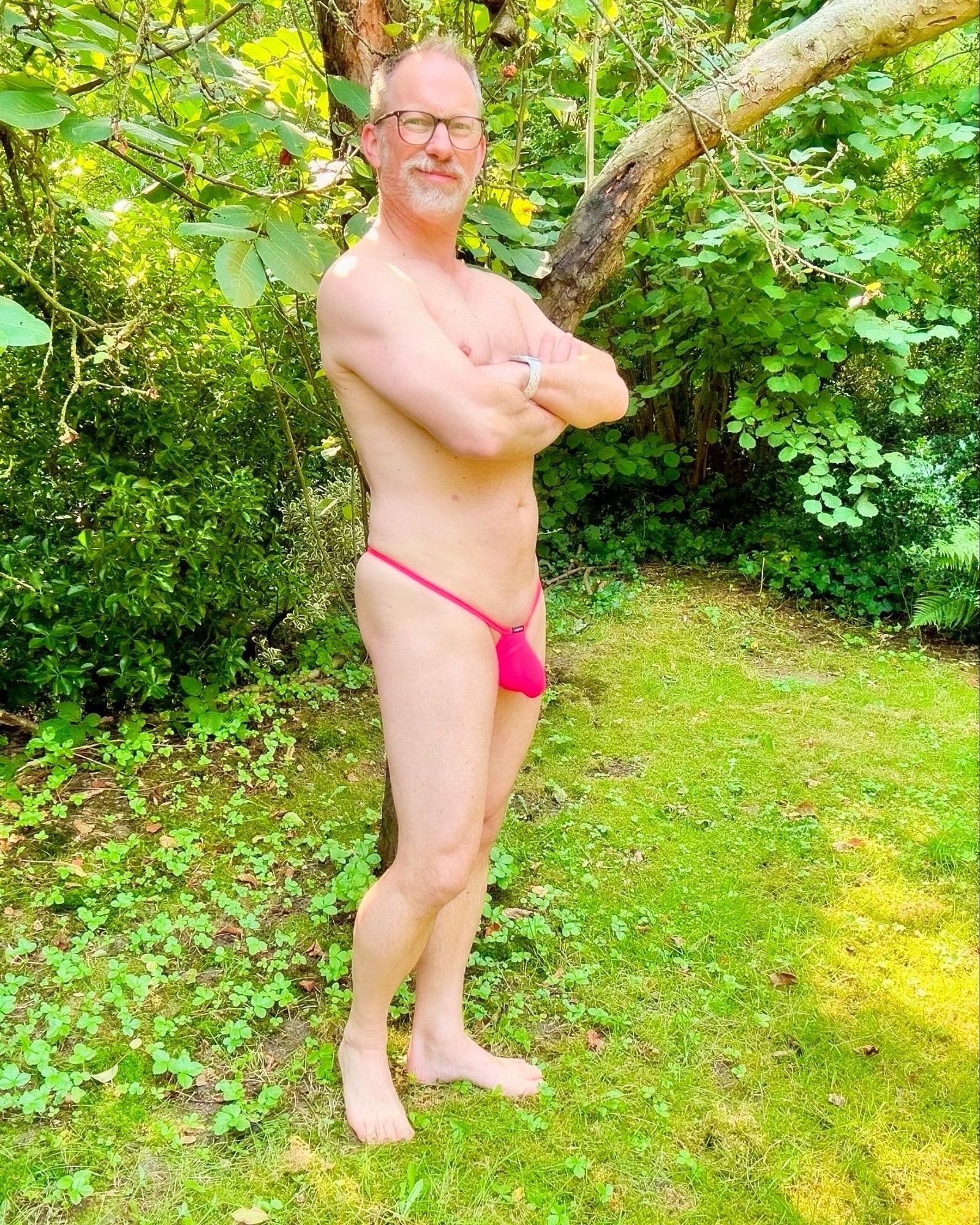 Another picture of me, only wearing that pink manthong, standing in the backyard in front of a tree. Facing the camera, bulge on display