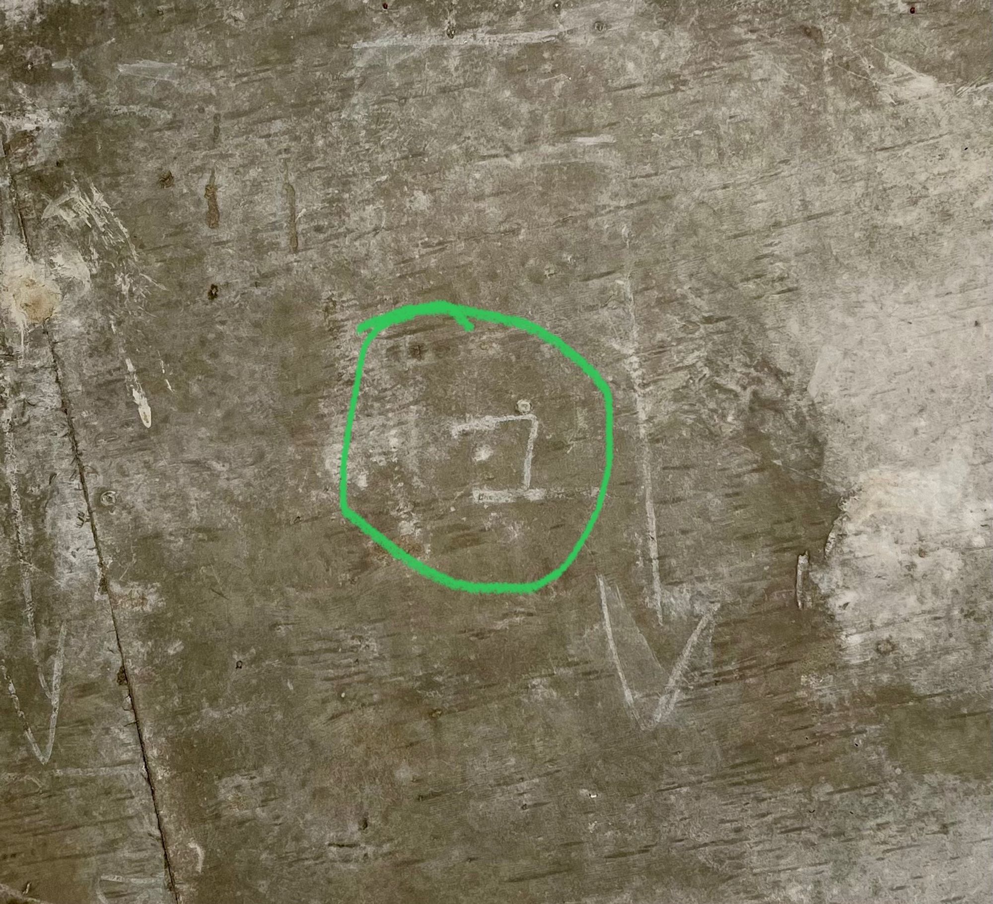 A raw concrete ceiling with various markings visible, including an arrow and something that looks like the Hebrew letter bet