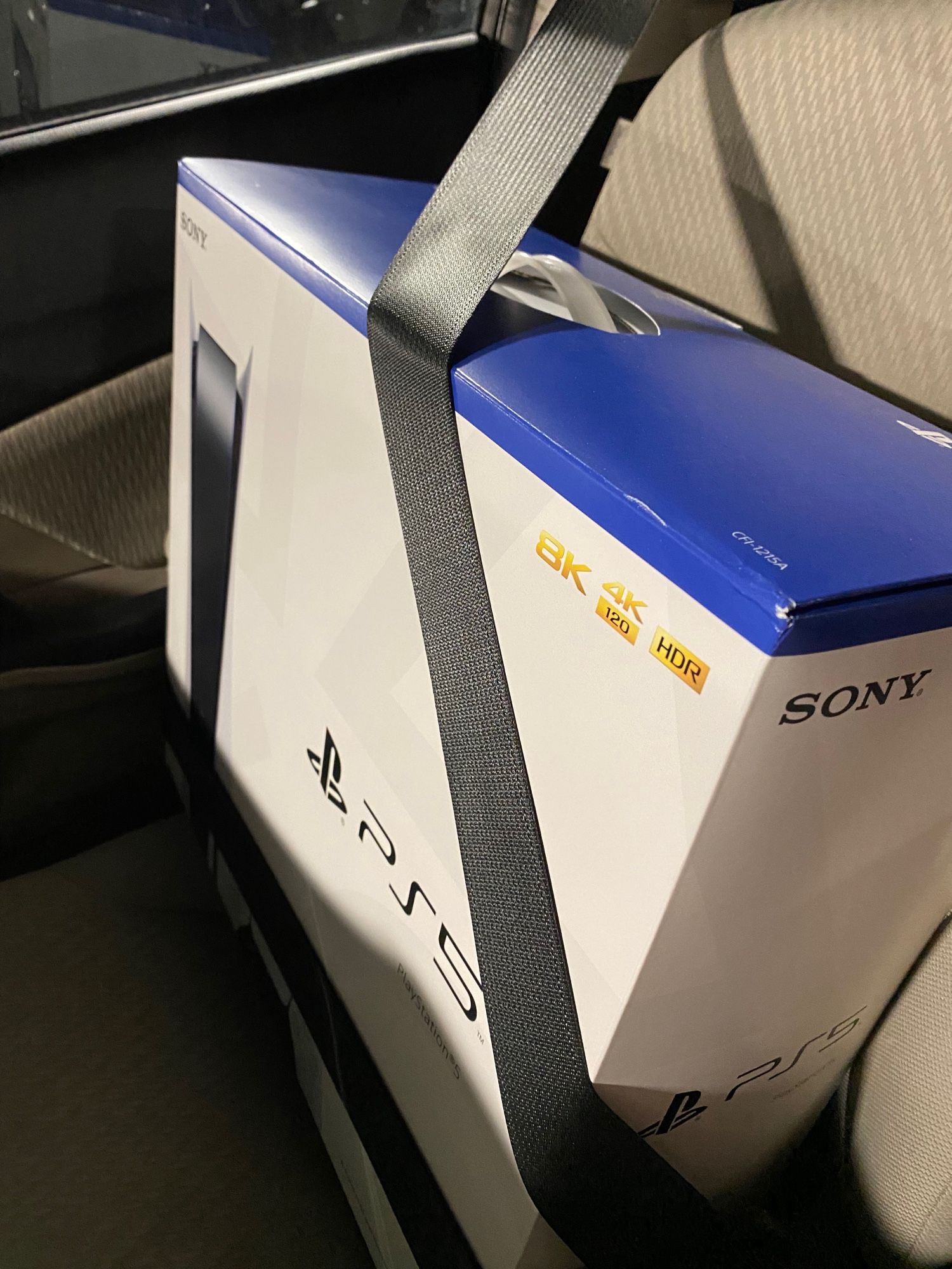 A PS5 box buckled into the passenger seat of Jett’s car, Gwaihir. There’s presumably a PS5 inside.