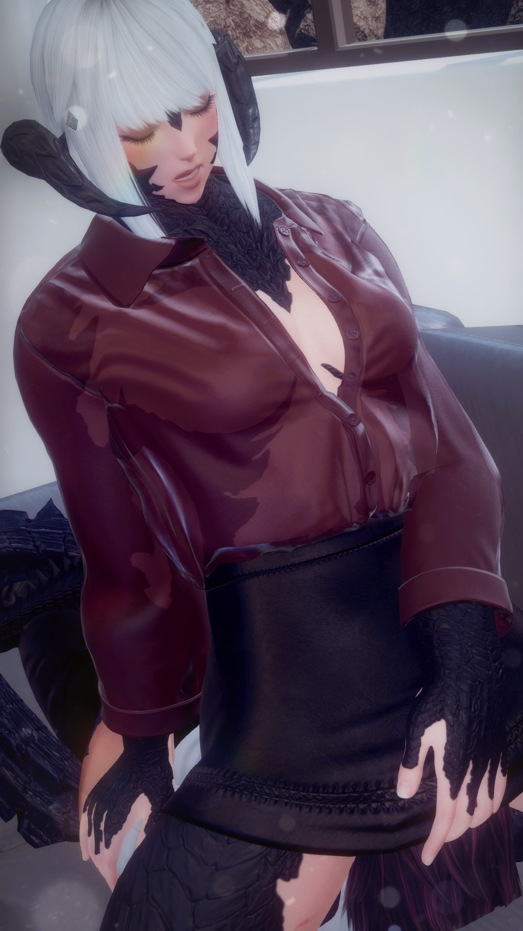 Dorgono sits upon a grey couch in a modern-looking room, dressed in a partially transparent wine red button-up shirt and an opaque black pencil skirt. Beneath her, Zaya Dalamiq lays on her back, her face obscured by Dorgono's skirt.