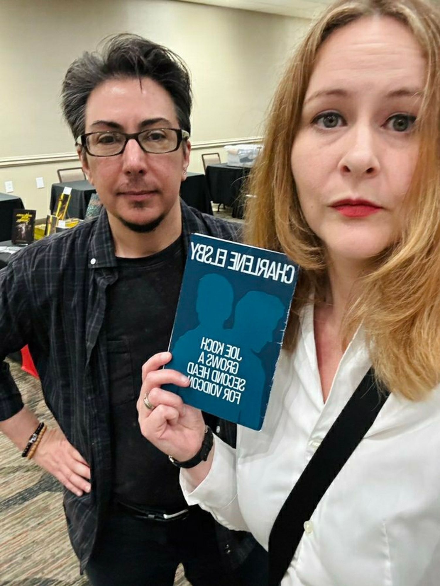 Joe Koch looking basically expressionless despite inner joy beside the brilliant Charlene Elsby. Charlene holds a copy of her chapbook entitled "Joe Koch Grows a Second Head for Voidcon."