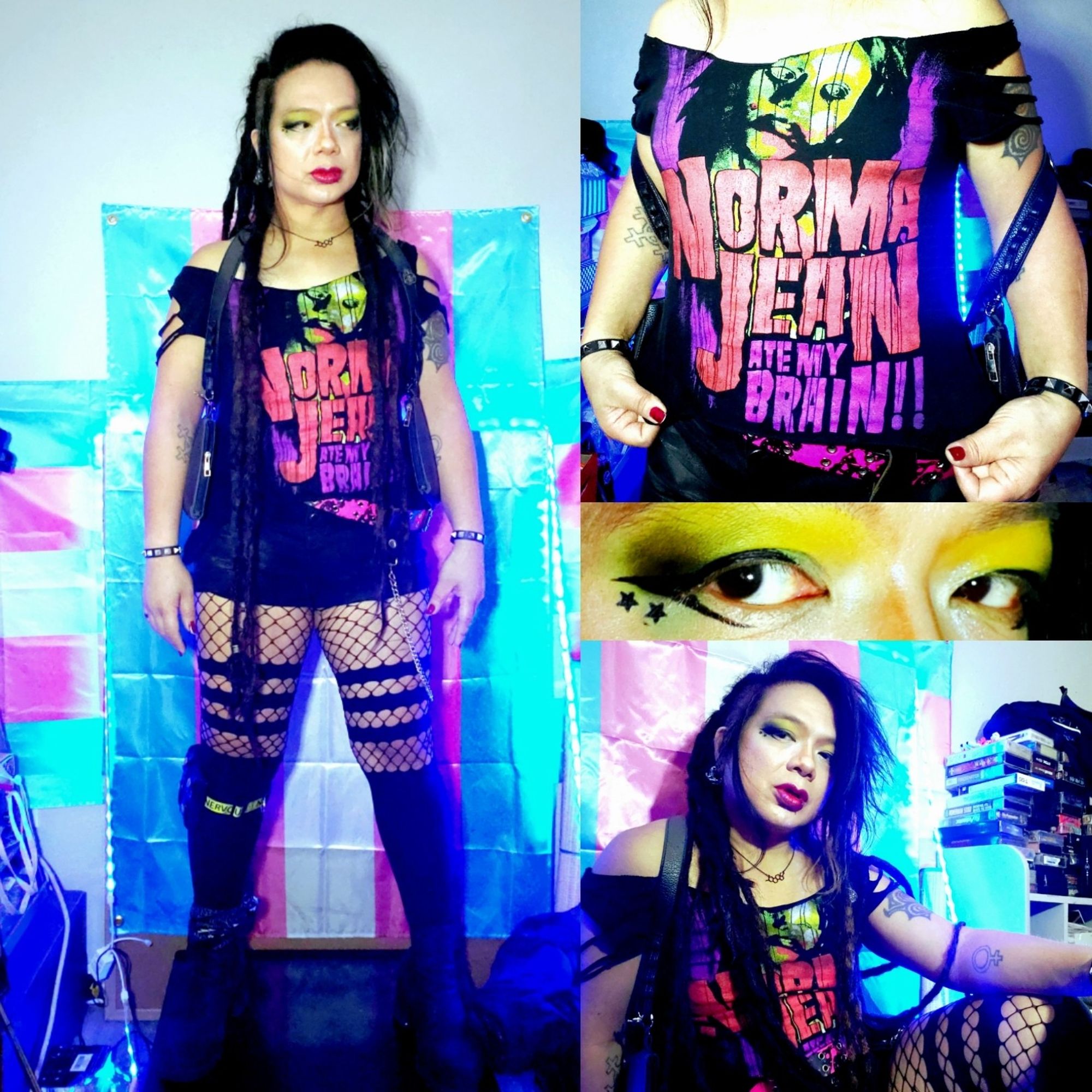 4 panel pic of Kei's outfit.
Left tall panel is head to toe.
Black Chelsea Heeled boots and black tights opaque from knees down and banded fishnet on top, right calf has yellow NERVOUS dog collar with black speedloader ammo holder, black high waisted shorts, single row pyramid bracelets and holster harness, cut up NORMA JEAN tee, Estrogen chain and red lipstick with shimmer, dreads down and hair volumized slightly. Top right panel is closeup of Tee, wide neck cut with chunk sleeves and ragged trim bottom, green ZombieGirl and in red NORMA JEAN and in purple ATE MY BRAIN.
Middlenright panel is closeup of eyes, white into yellow into green with black dust eyeshadow and twin stars under liner wings, lots of shimmer.
Bottom right panel is waist up pic of Kei reclined and Manifesting Vibes for the day ahead.
All pics color saturated and contrast boosted with Trans Pride Flags for backdrop.