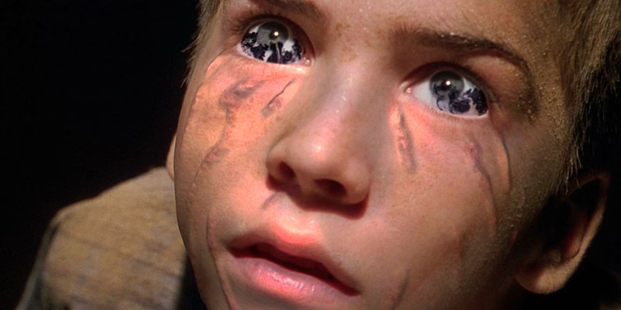 A frame from the X-Files movie showing a young boy with black goo/oil in his eyes, suggesting that he is being taken over by something