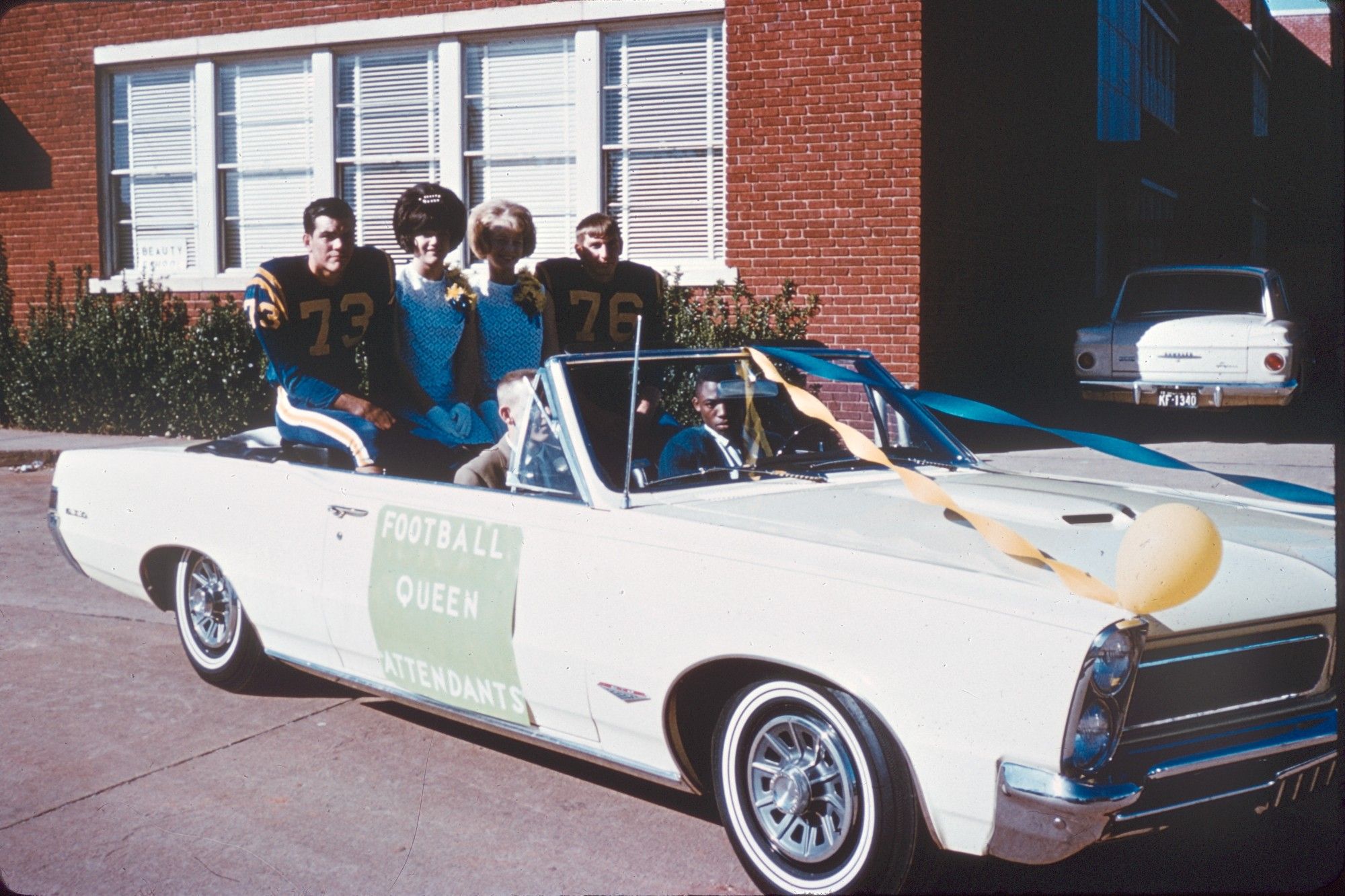 1950s open top convertible with football players and homecoming queen attendants riding in the back