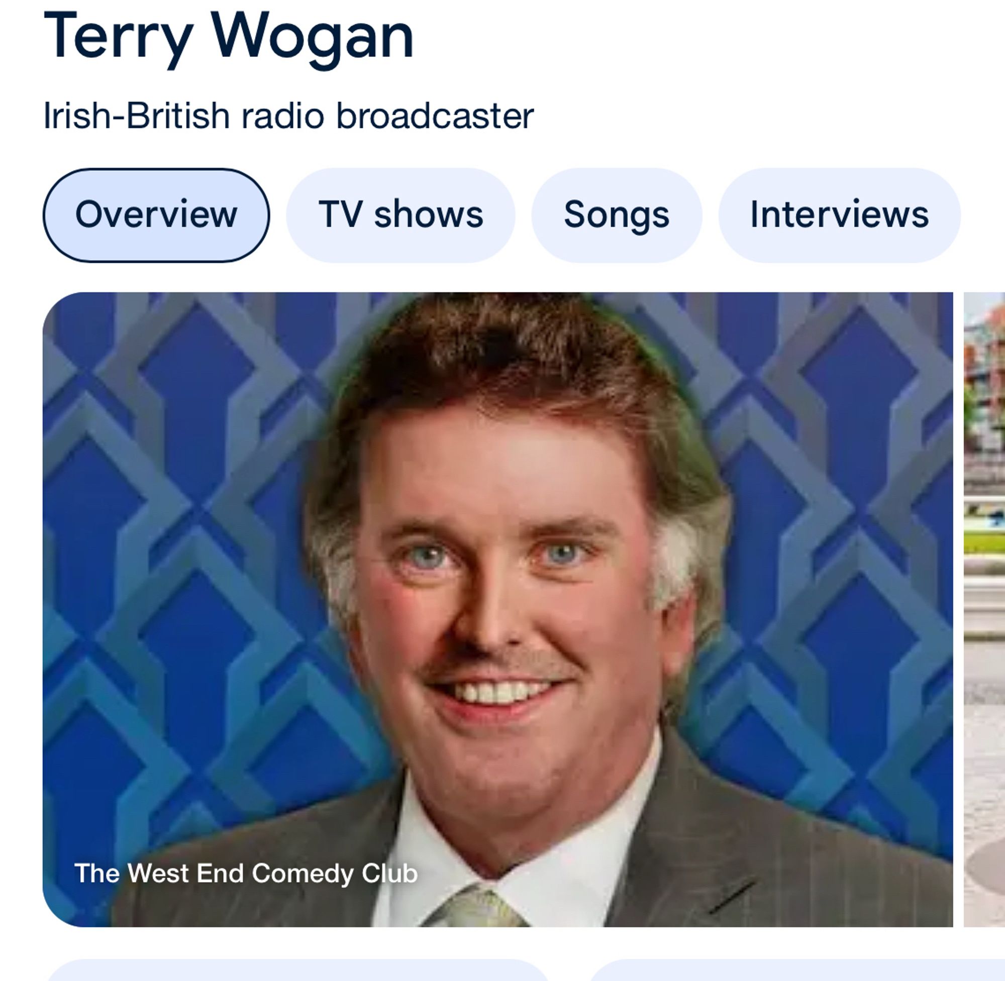 A head shot of a smiling man with grey hair at the temples. It is someone impersonating Terry Wogan.