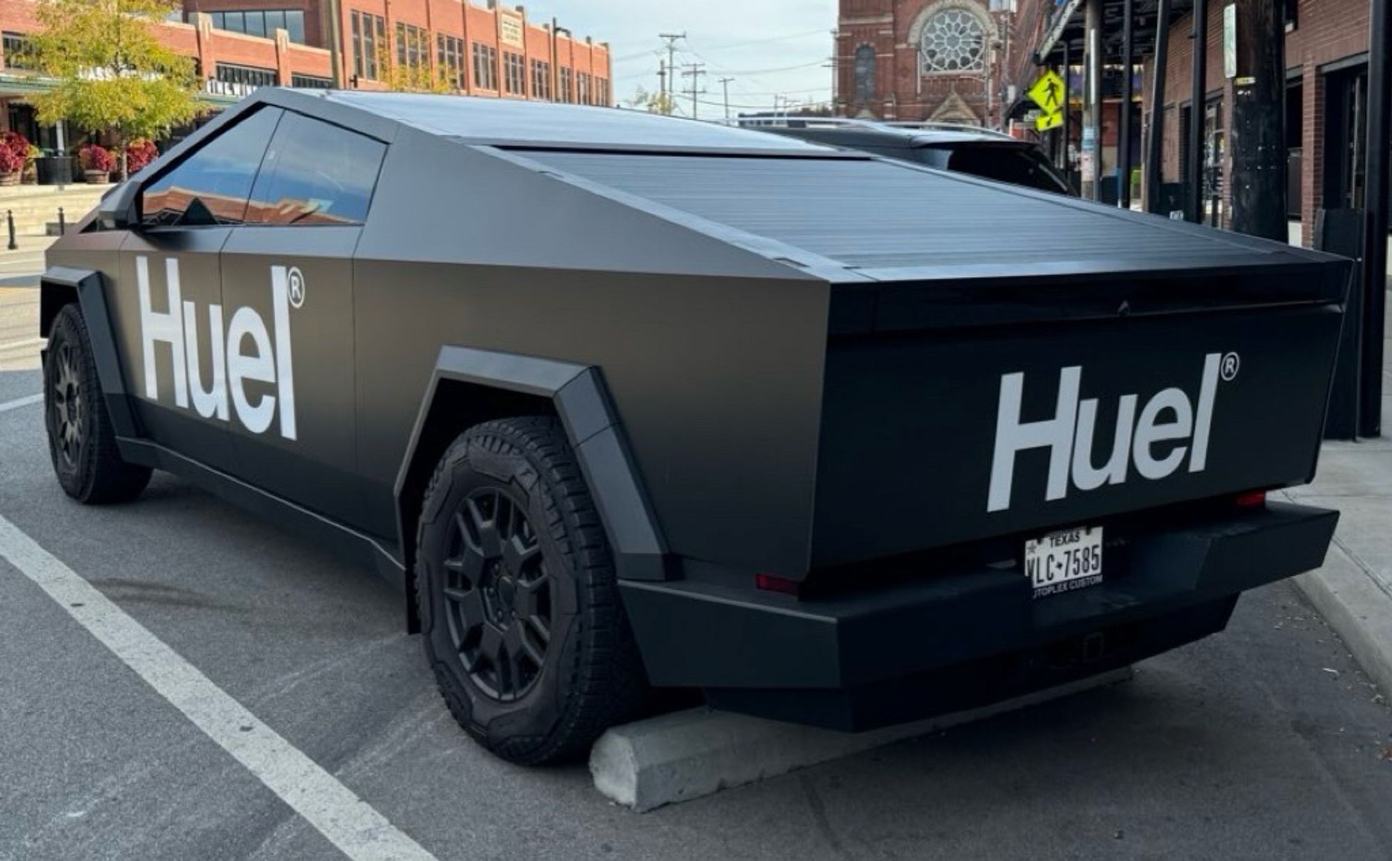 A Tesla Cybertruck wrapped in matte black with Huel meal replacement shake branding on all sides